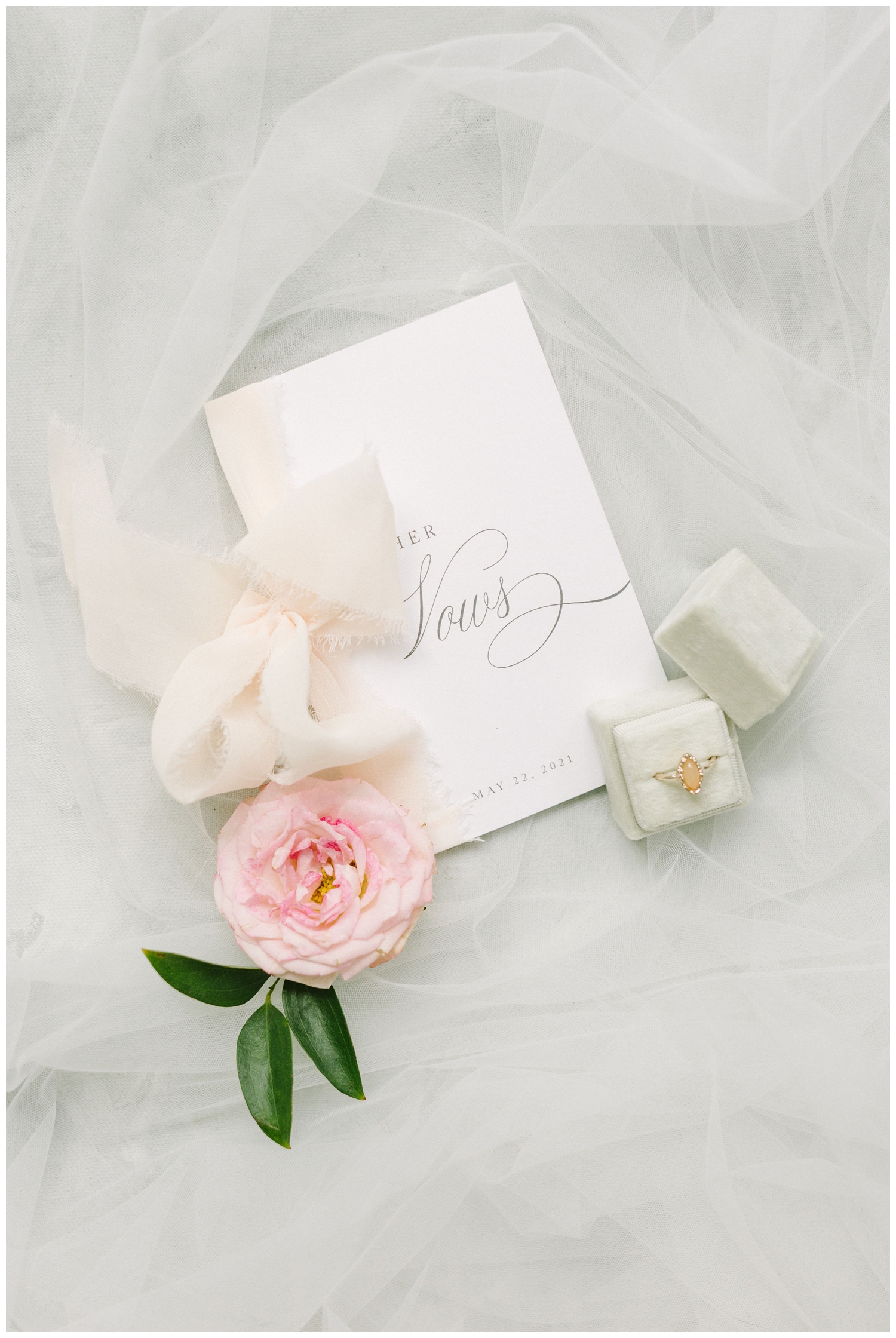 white vow books with peach wedding ring together as wedding flatlay