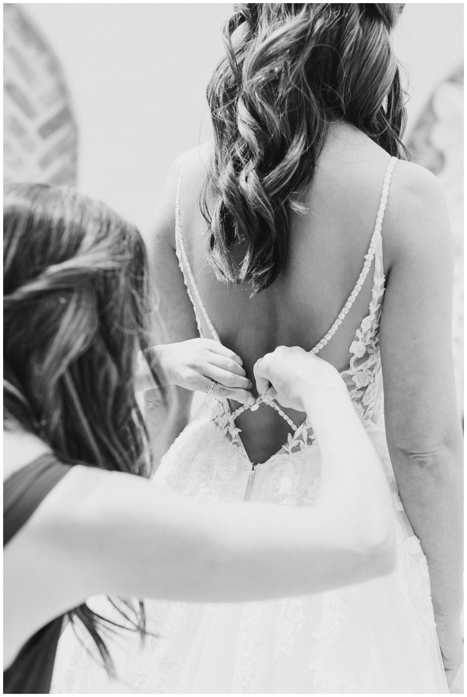 black and white photo of bride getting wedding gown buttoned