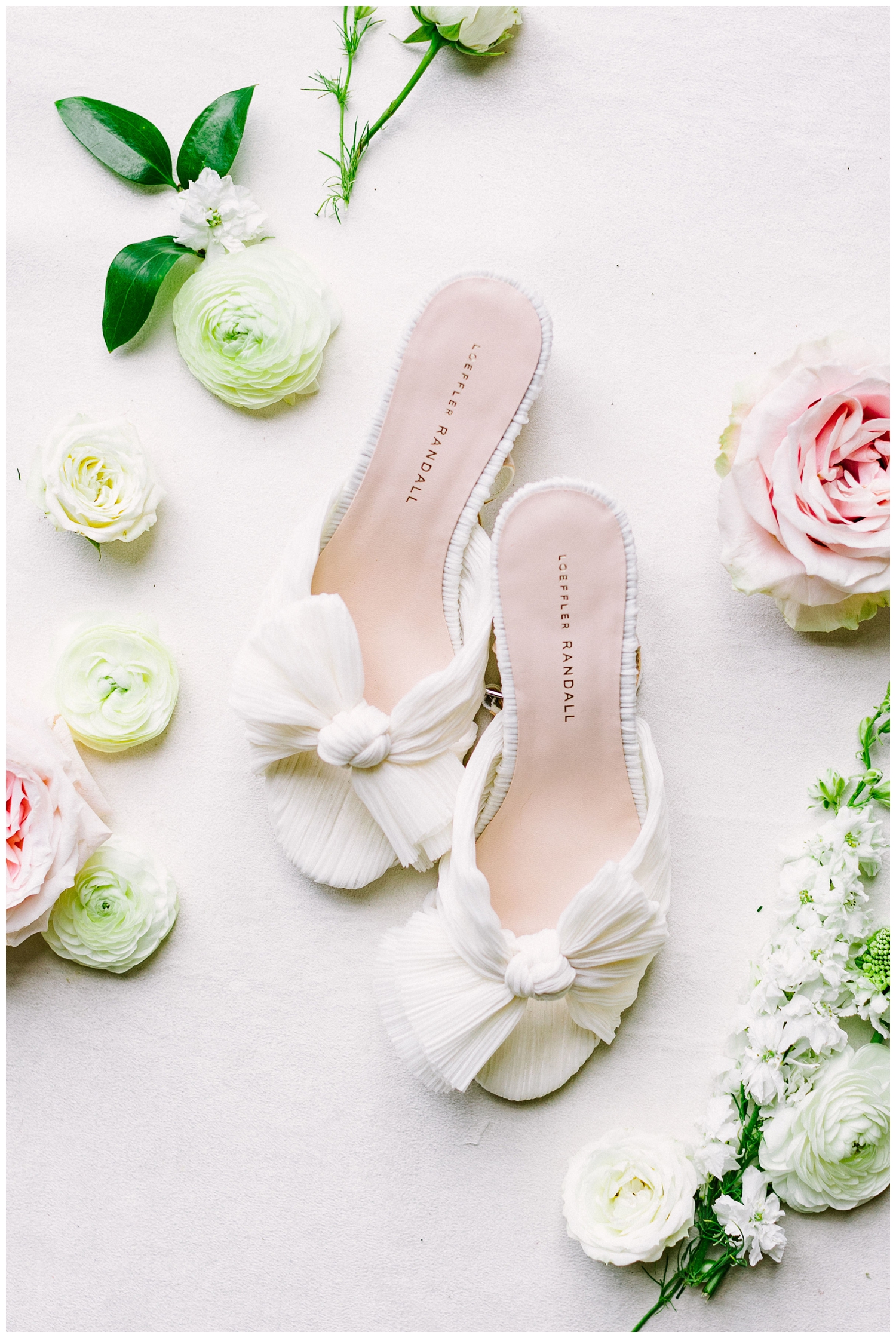 white wedding heels with florals surrounding them