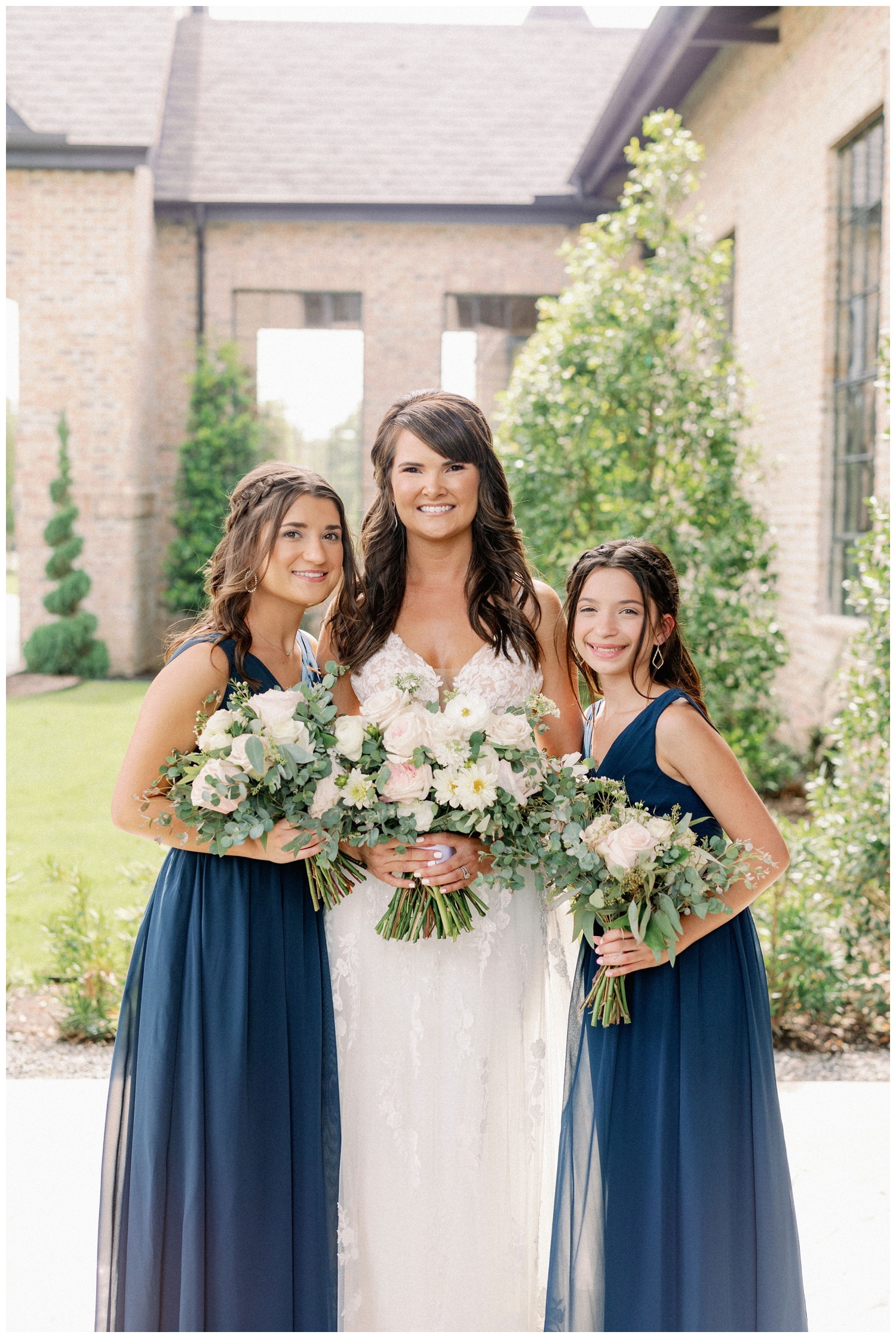 bride with daughters in navy dresses outside Iron Manor wedding venue in Montgomery, Texas