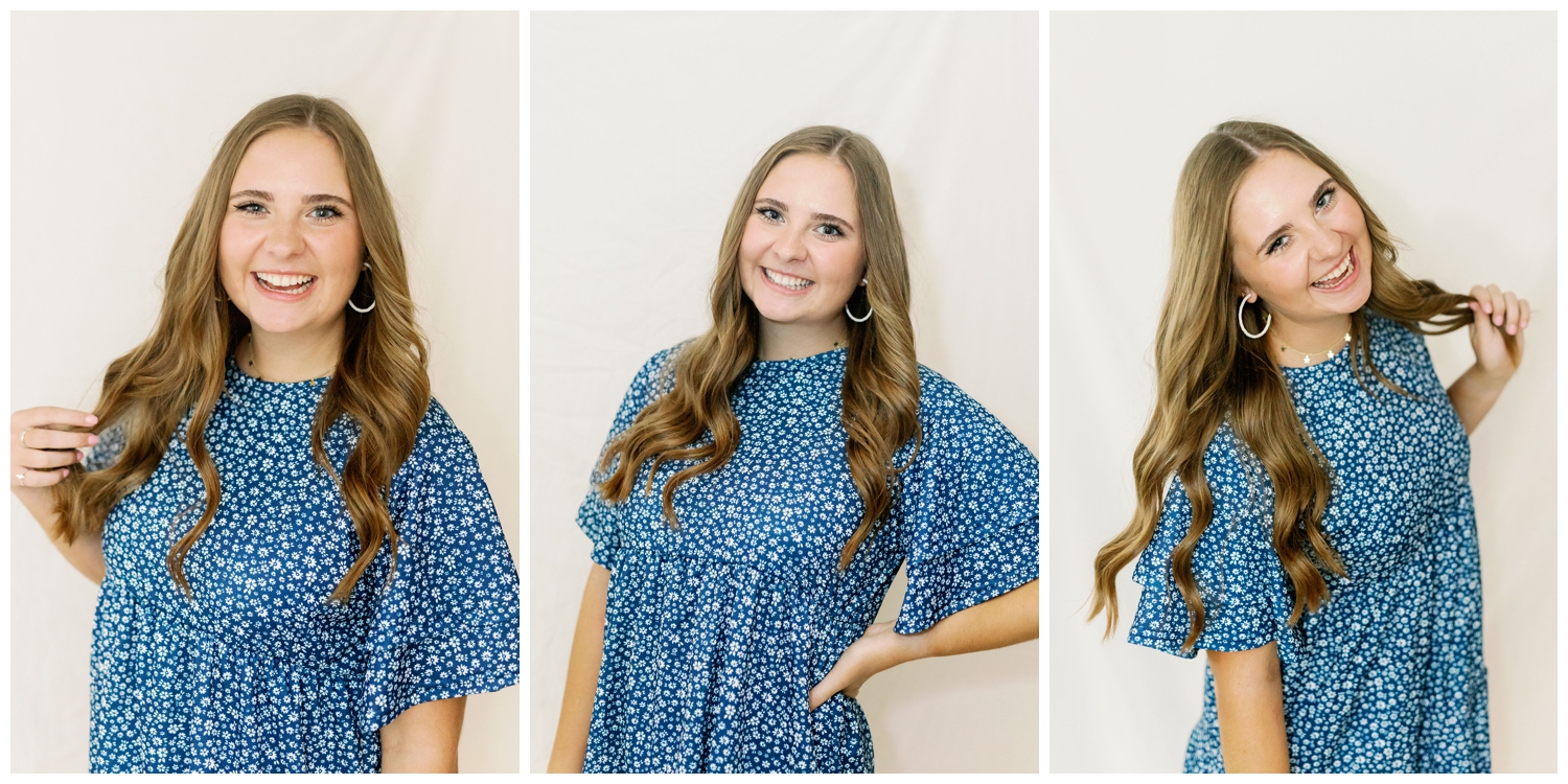 high school senior girl posing against white wall standing in blue dress