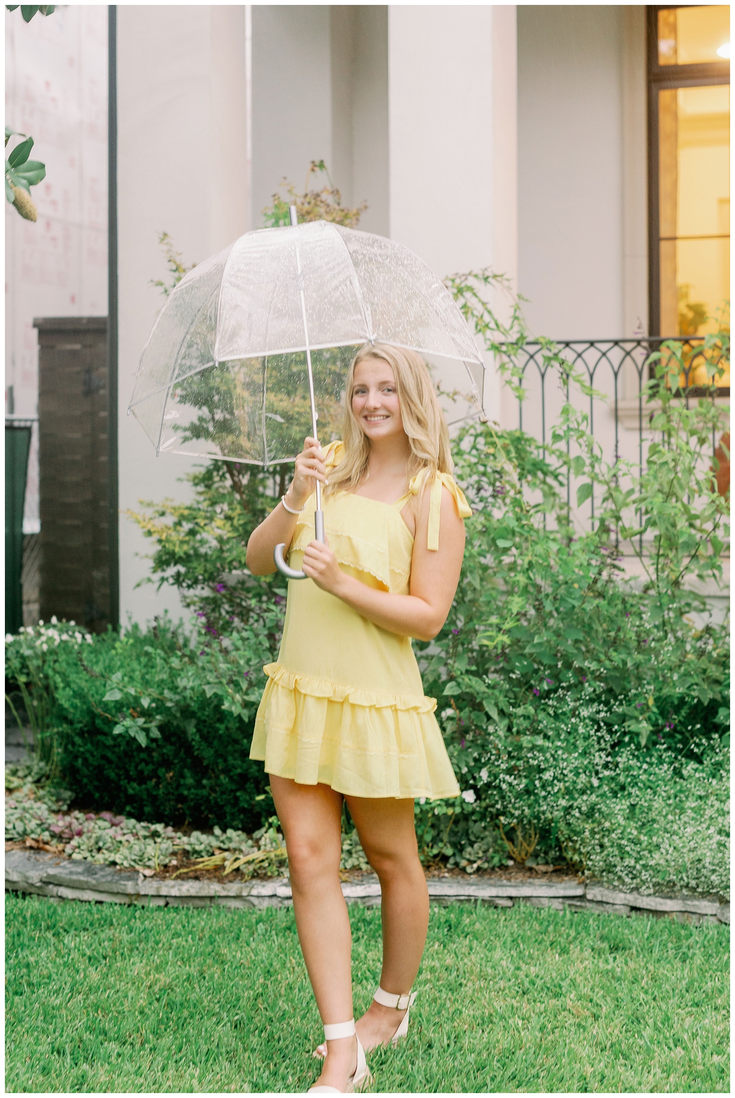high school senior girl standing in grass with clear umbrella in Houston Texas