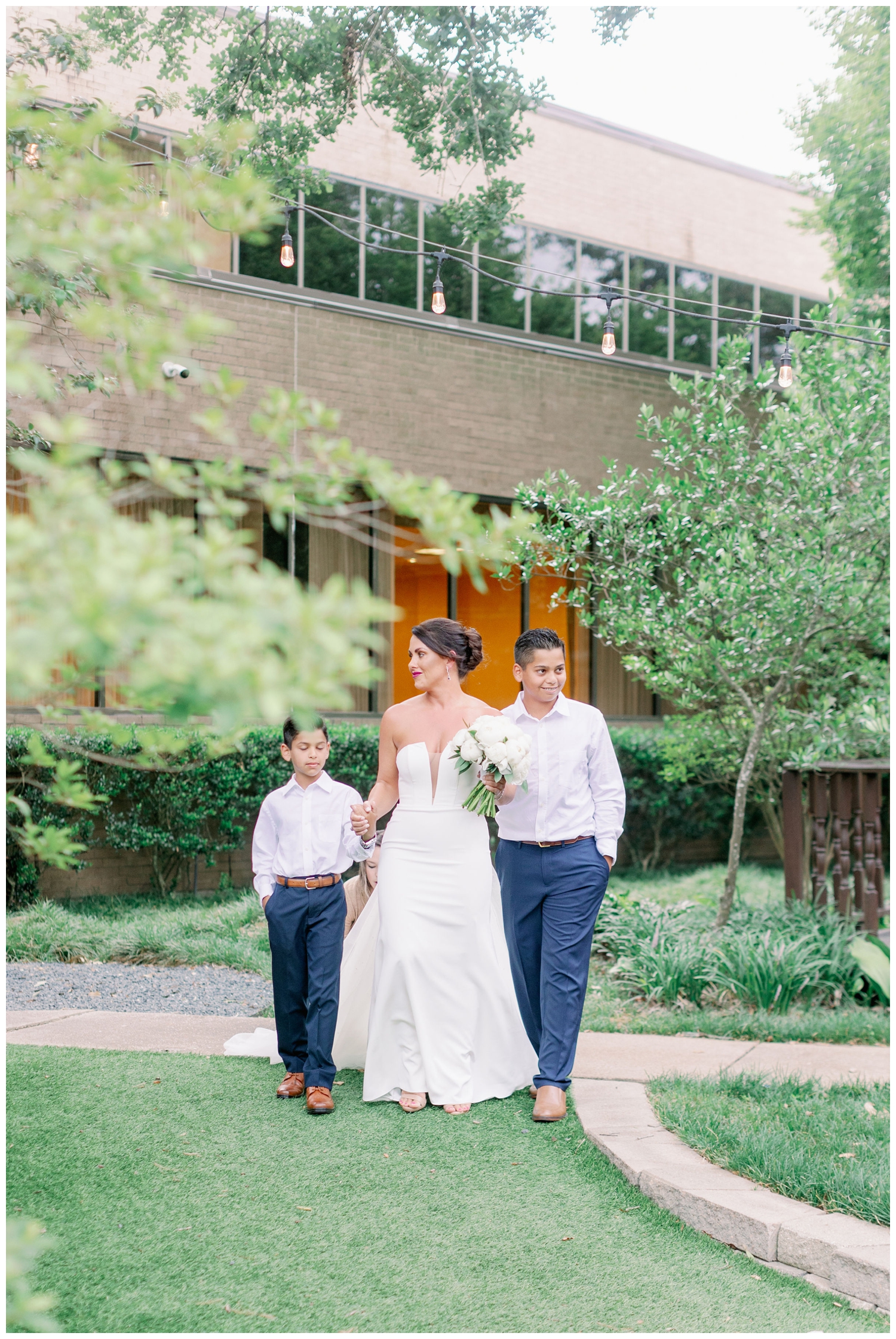 bride walking into ceremony with her two boys outside The Houstonian Hotel wedding