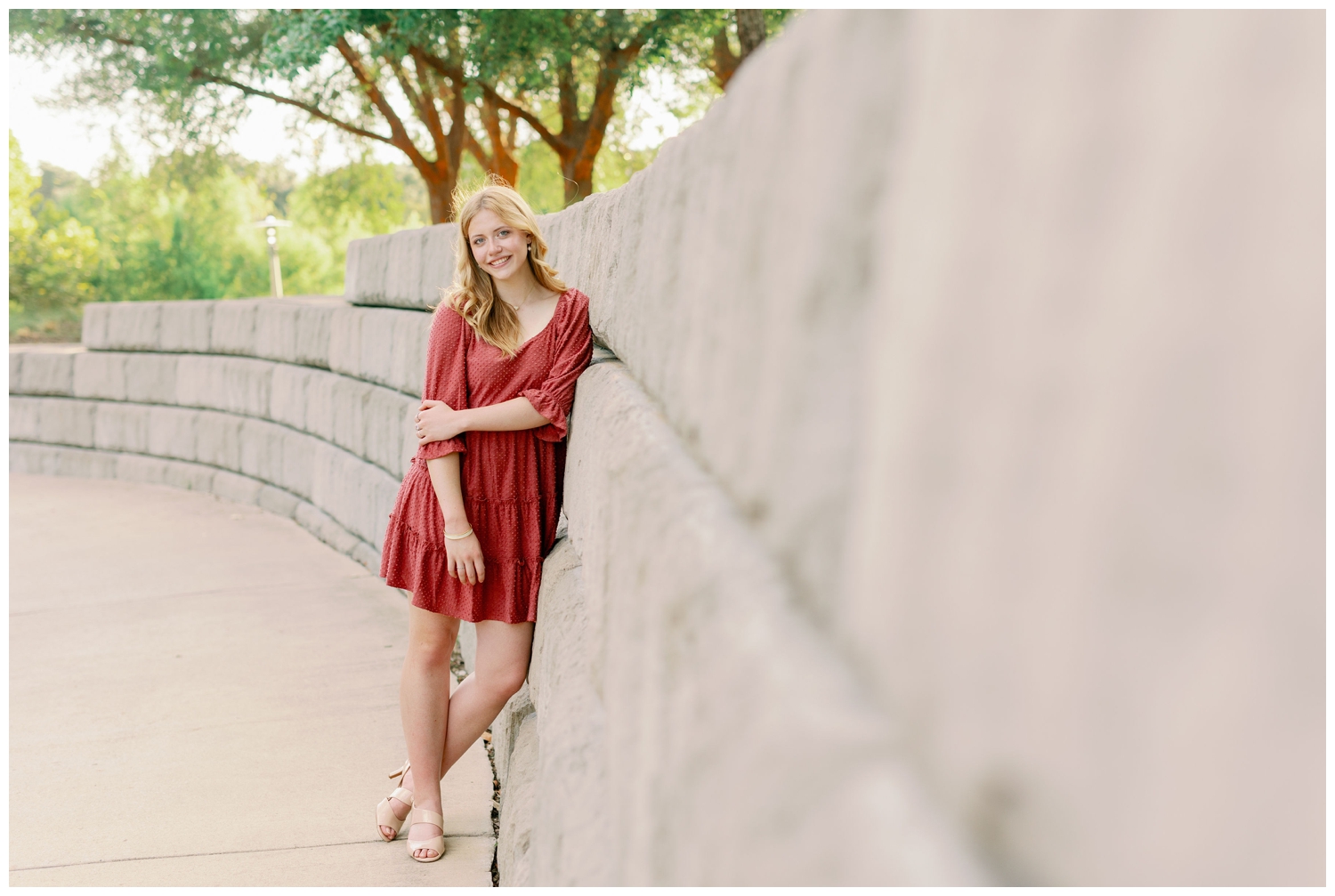 downtown Houston senior girl in coral dress leaning against gray column wall
