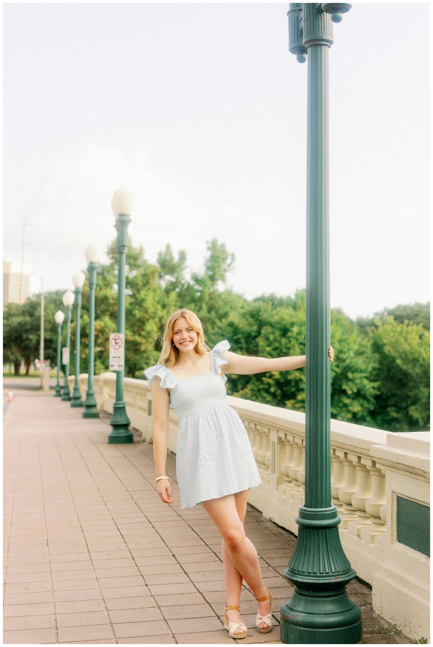 girl in blue dress holding onto lamp post on Sabine Bridge downtown Houston