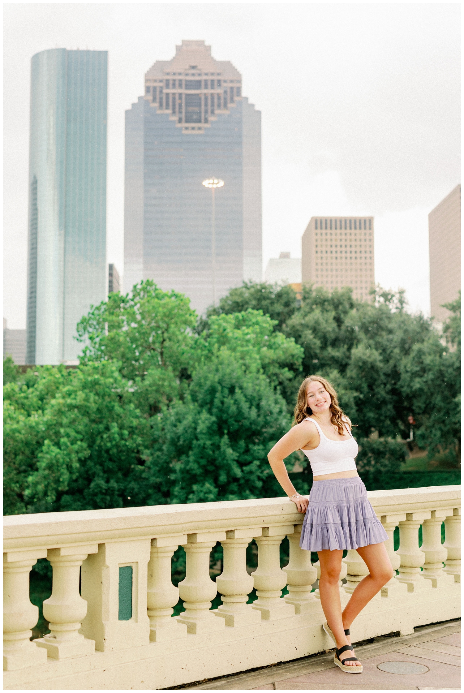 girl leaning on Sabine Bridge in front of Houston skyline