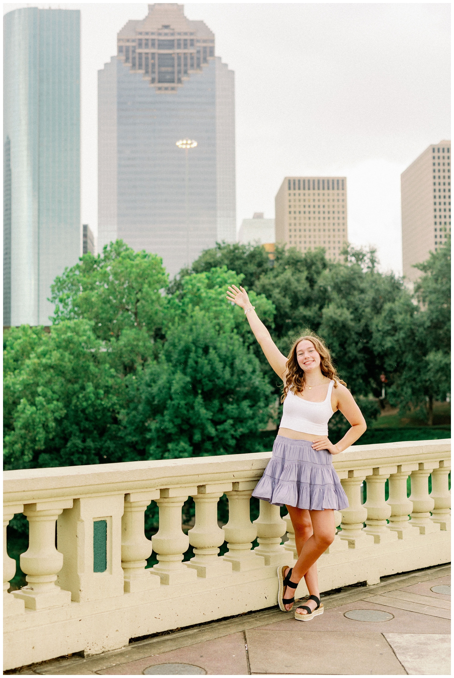 girl with arm in the air on Sabine Bridge with Houston skyline in background