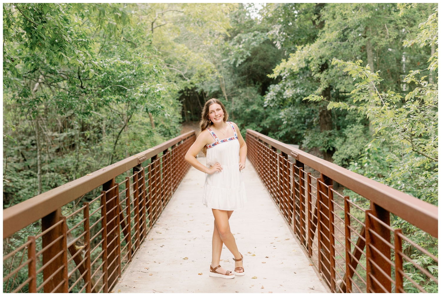 Senior photography Houston Arboretum girl in white dress standing on bridge