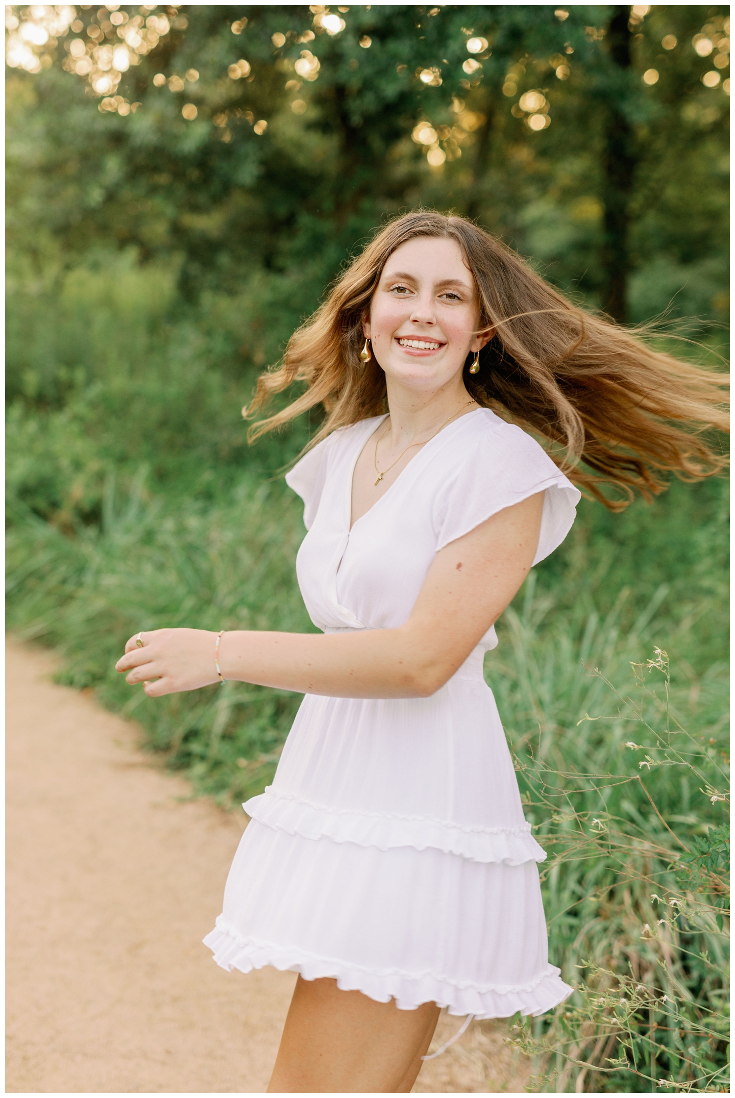 senior girl in white dress twirling at Houston Arboretum