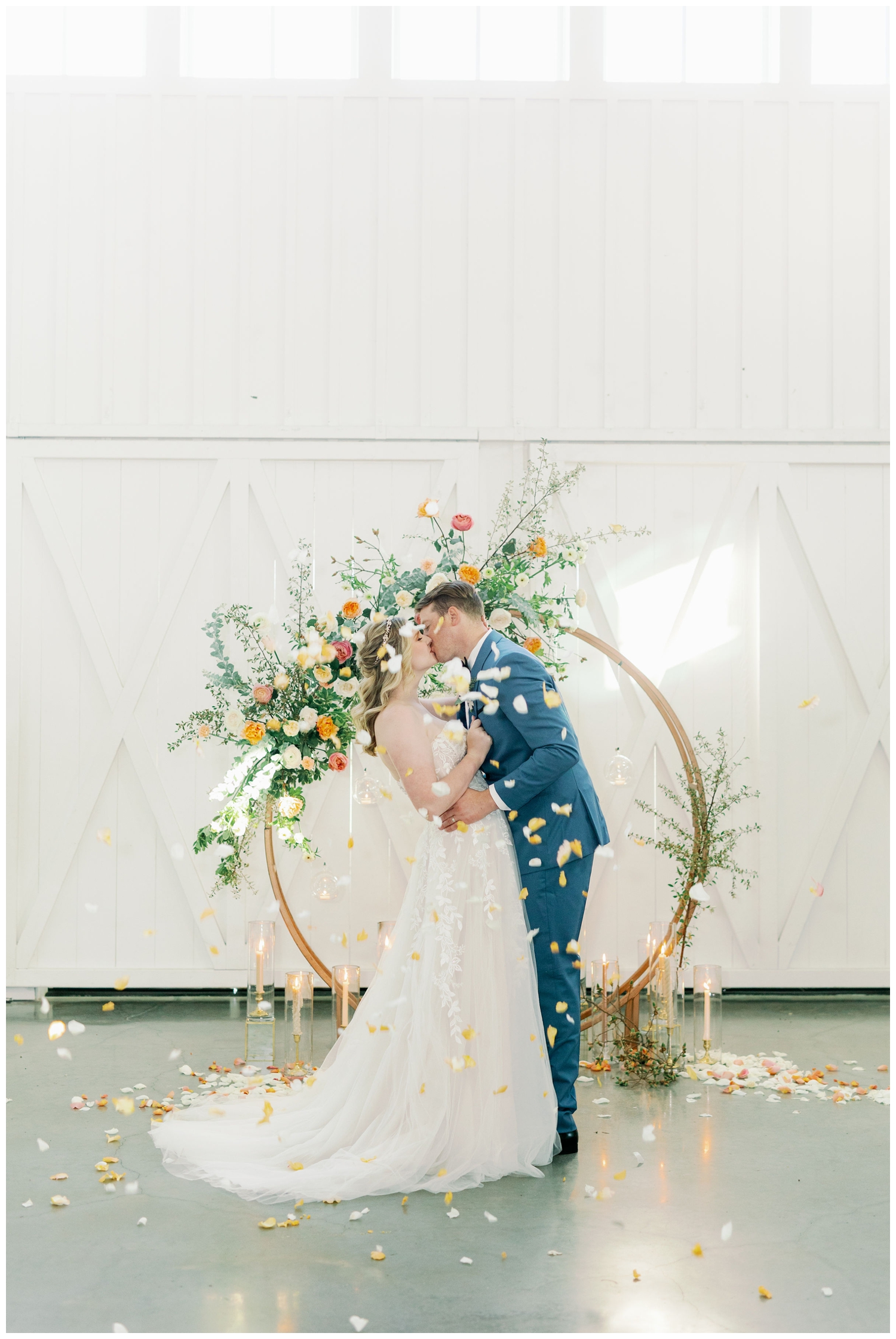 bride and groom kissing with rose petals being thrown at them