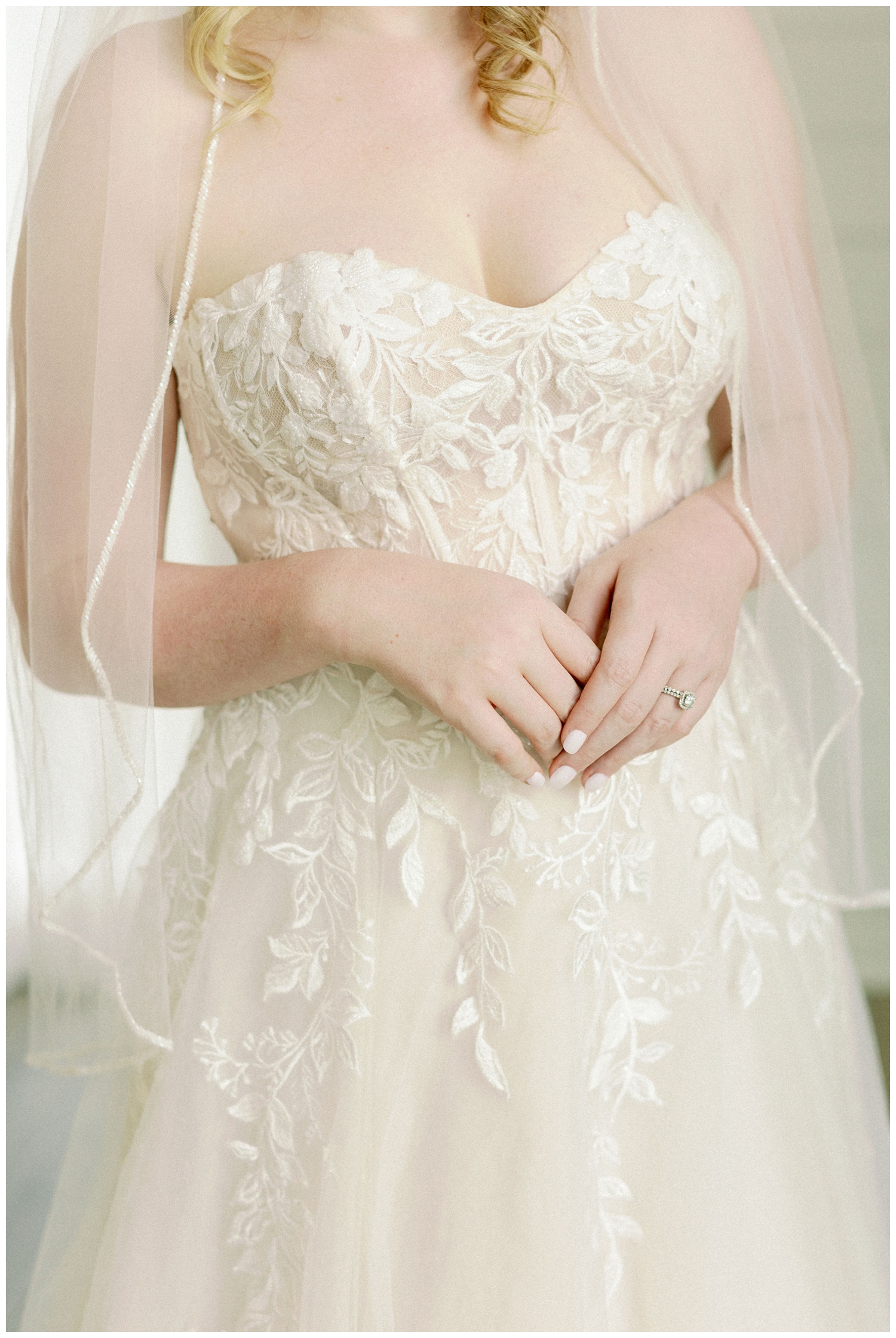 close up of brides hand at her waist with wedding gown and veil