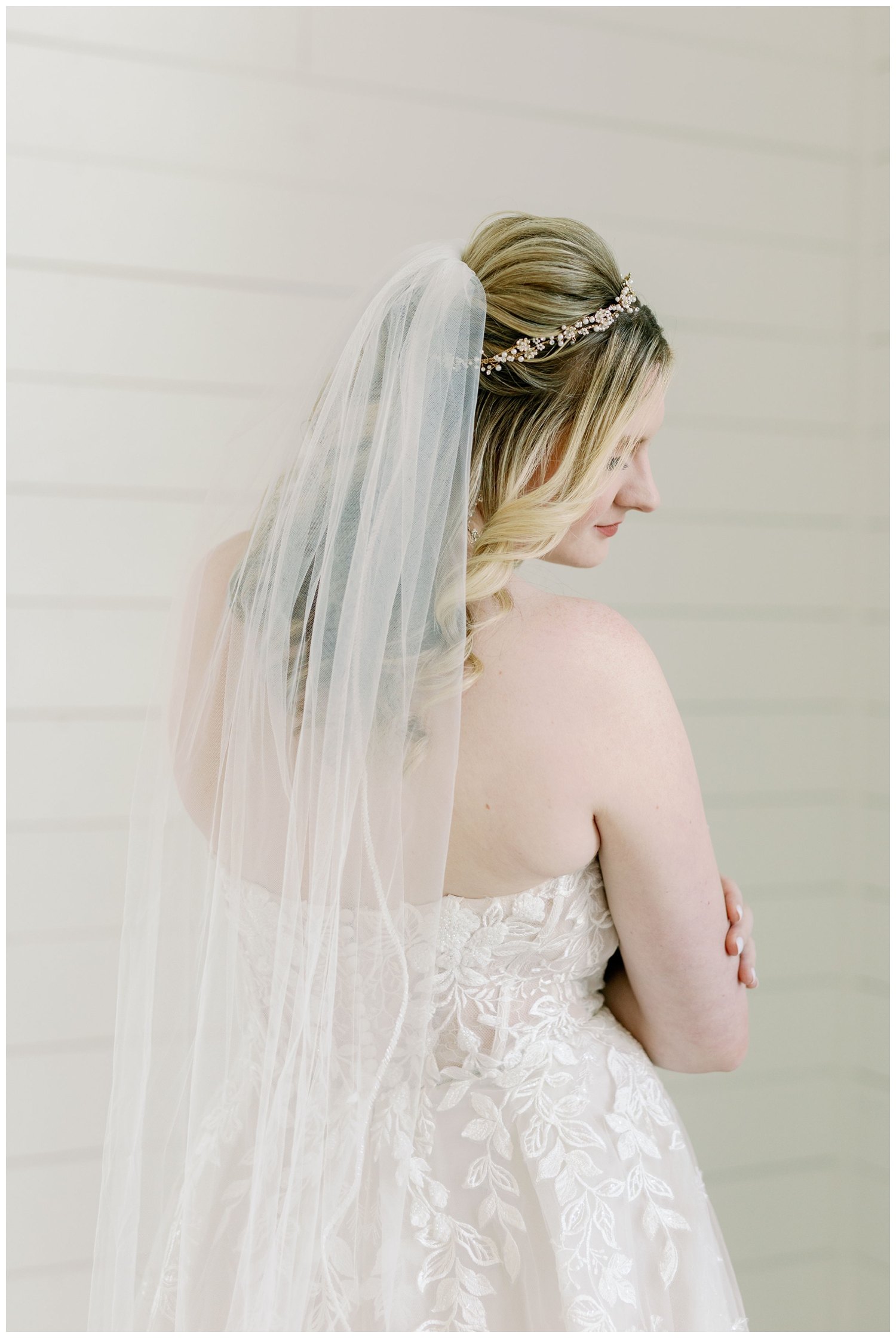 bridal portrait with bride looking over shoulder inside white barn reception space
