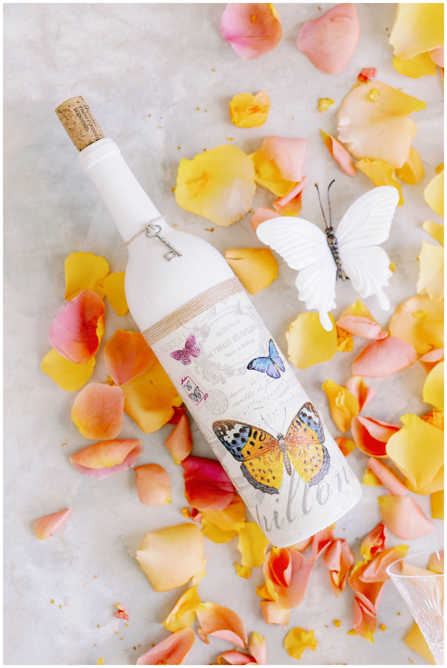 wine bottle with butterfly on it surrounding by peach florals