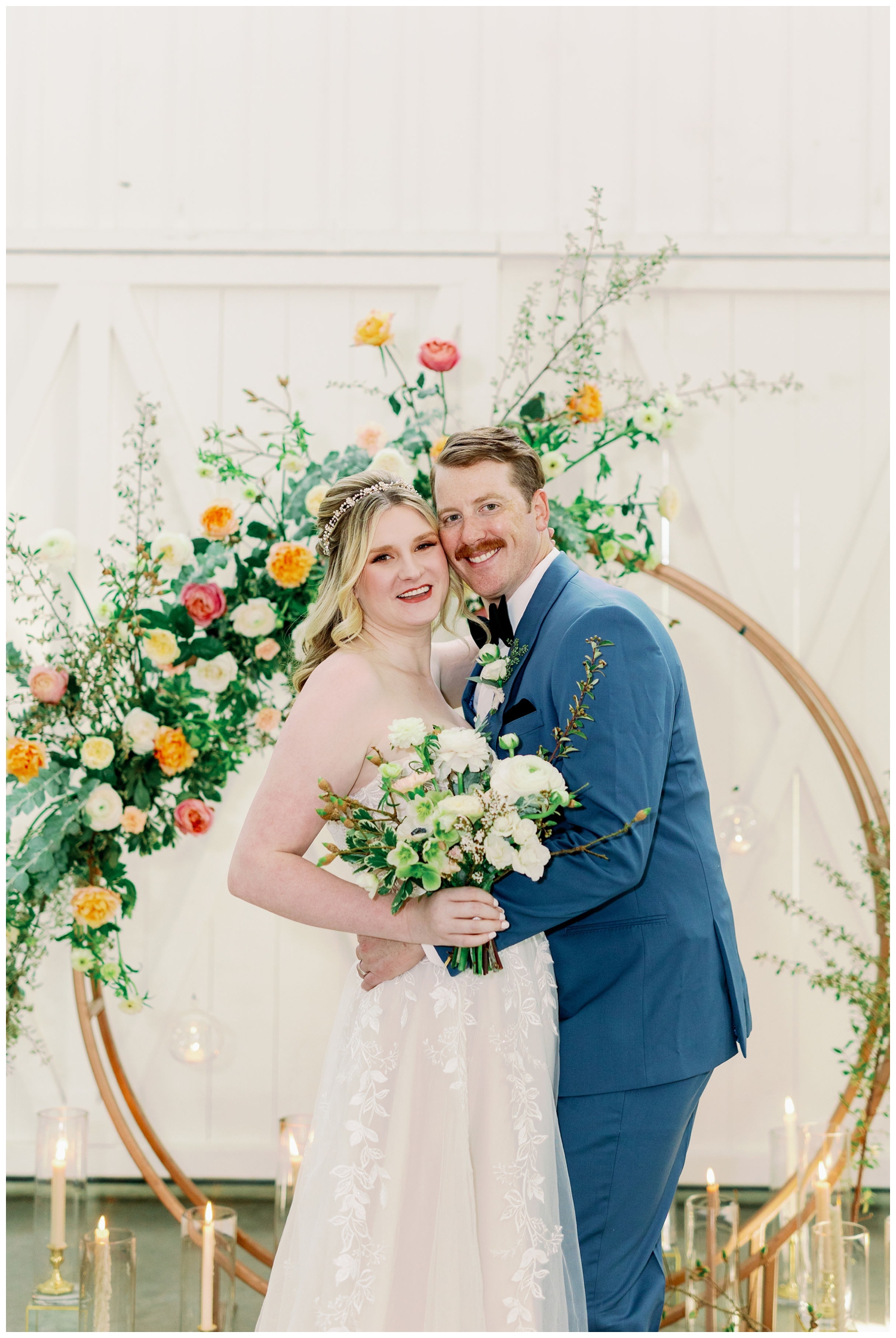 bride and groom cheek to cheek in front of gold hoop with floral installation