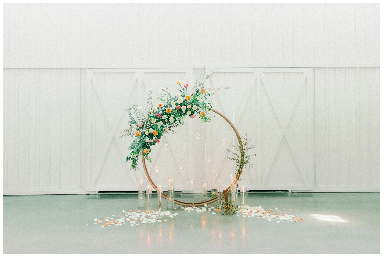 gold hoop installation with florals and candles and rose petals on floor inside The Farmhouse Wedding and Event Venue
