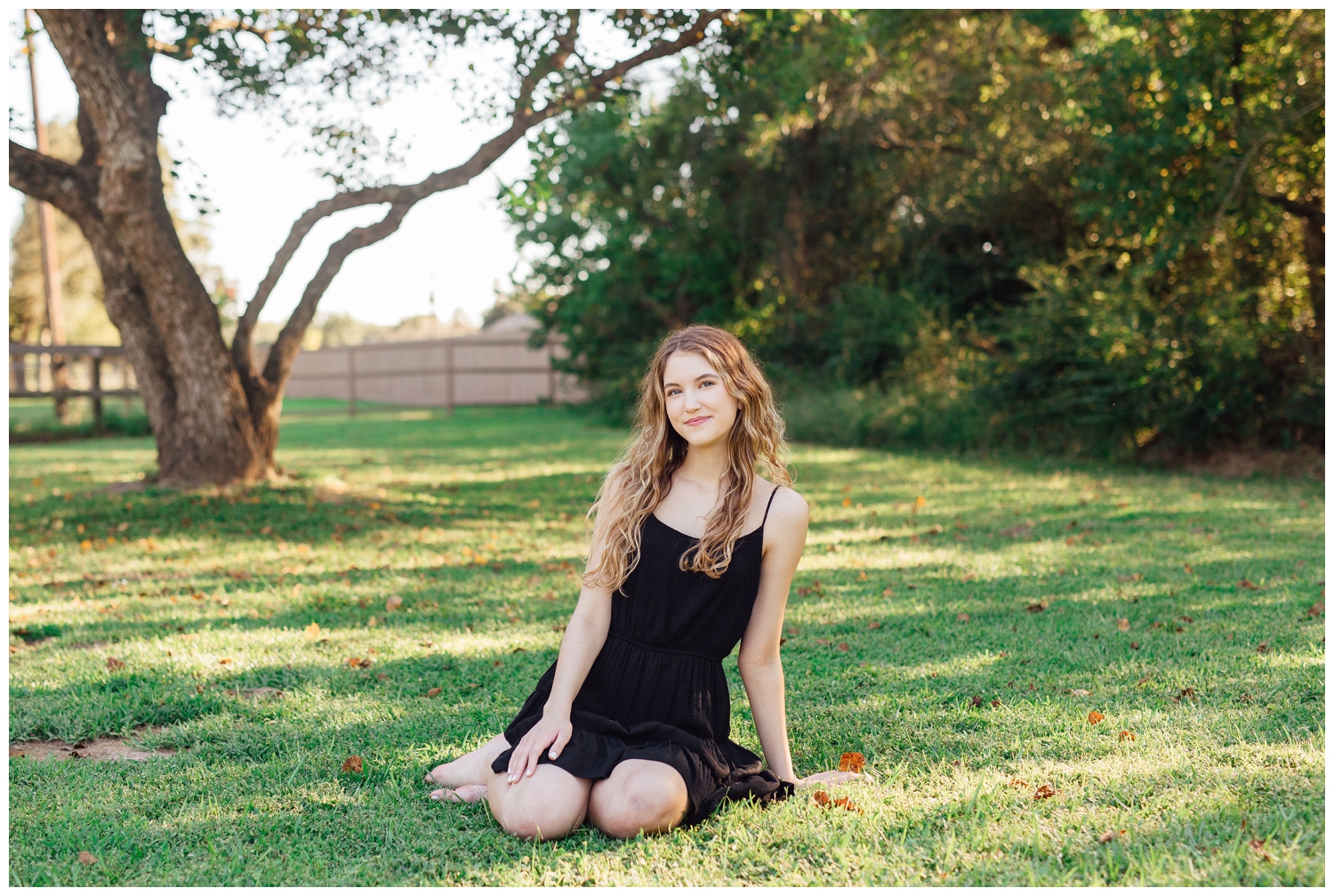 girl in black sundress sitting on grass under a tree colorful Houston senior photos