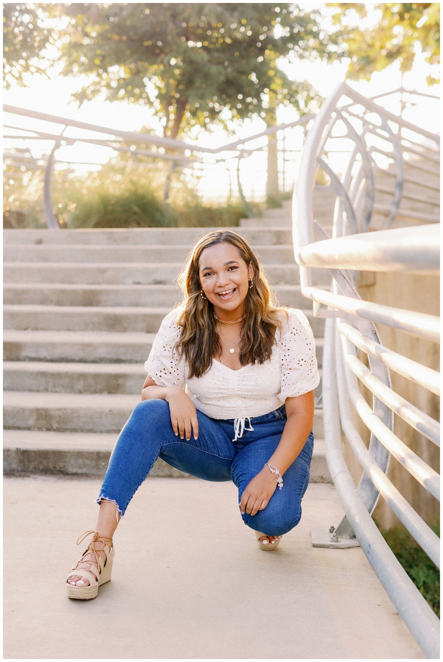 girl squatting and smiling for fall Houston senior photos on staircase by Sabine Street