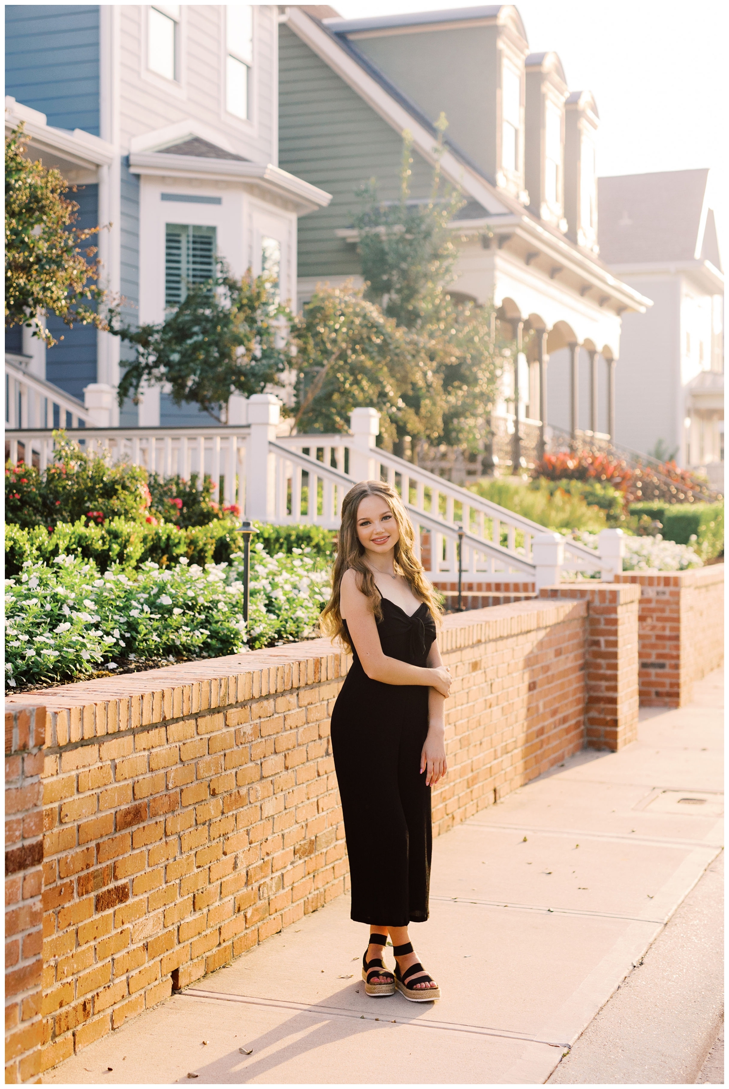 Galveston Beach senior session with girl in black jumpsuit standing in front of sidewalk