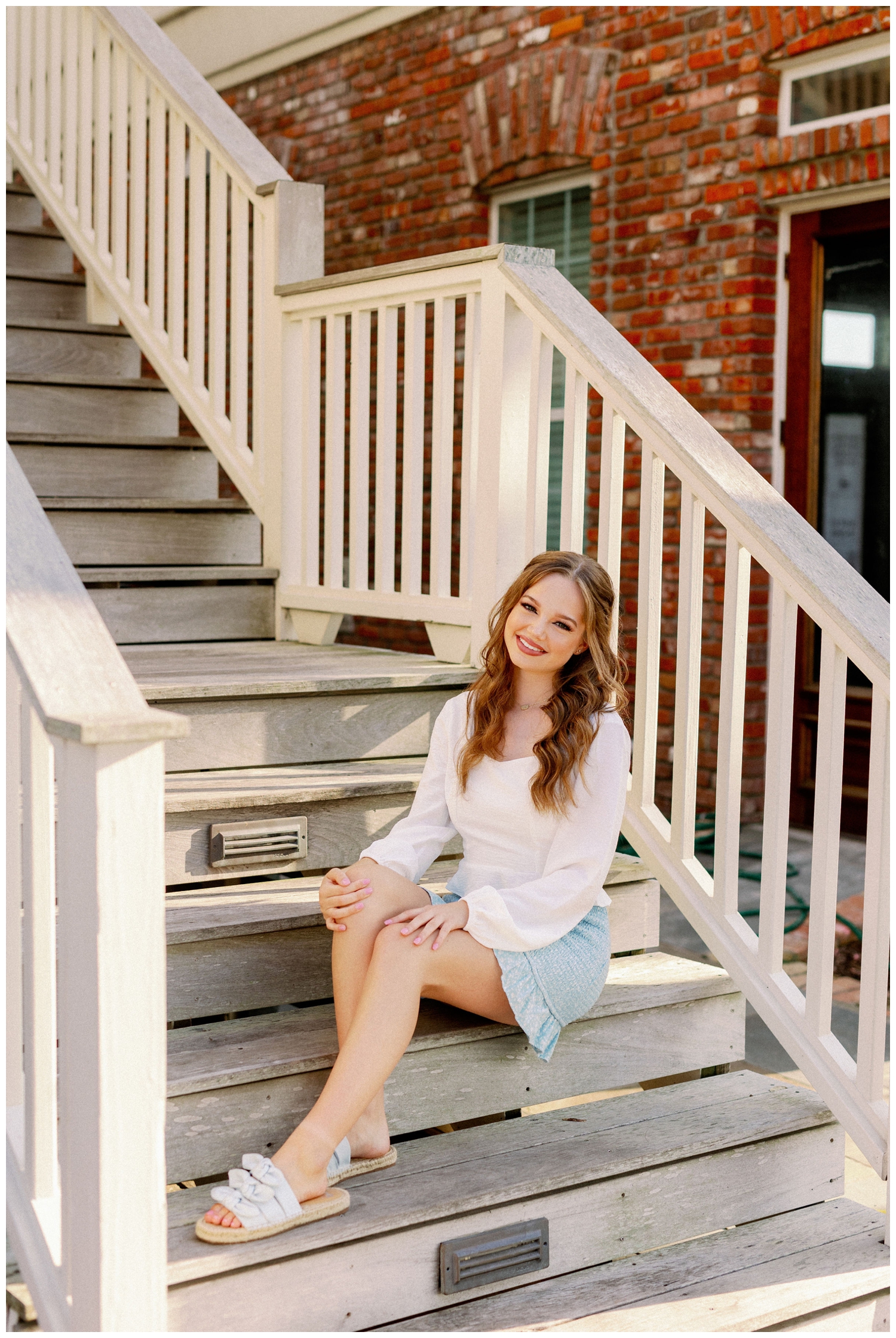 girl in blue skirt and white blouse sitting on white stairs in Galveston Texas
