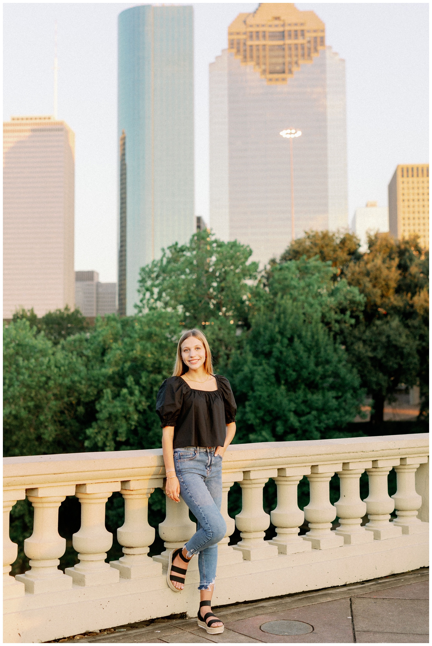 girl in black shirt and jeans standing in front of Houston skyline
