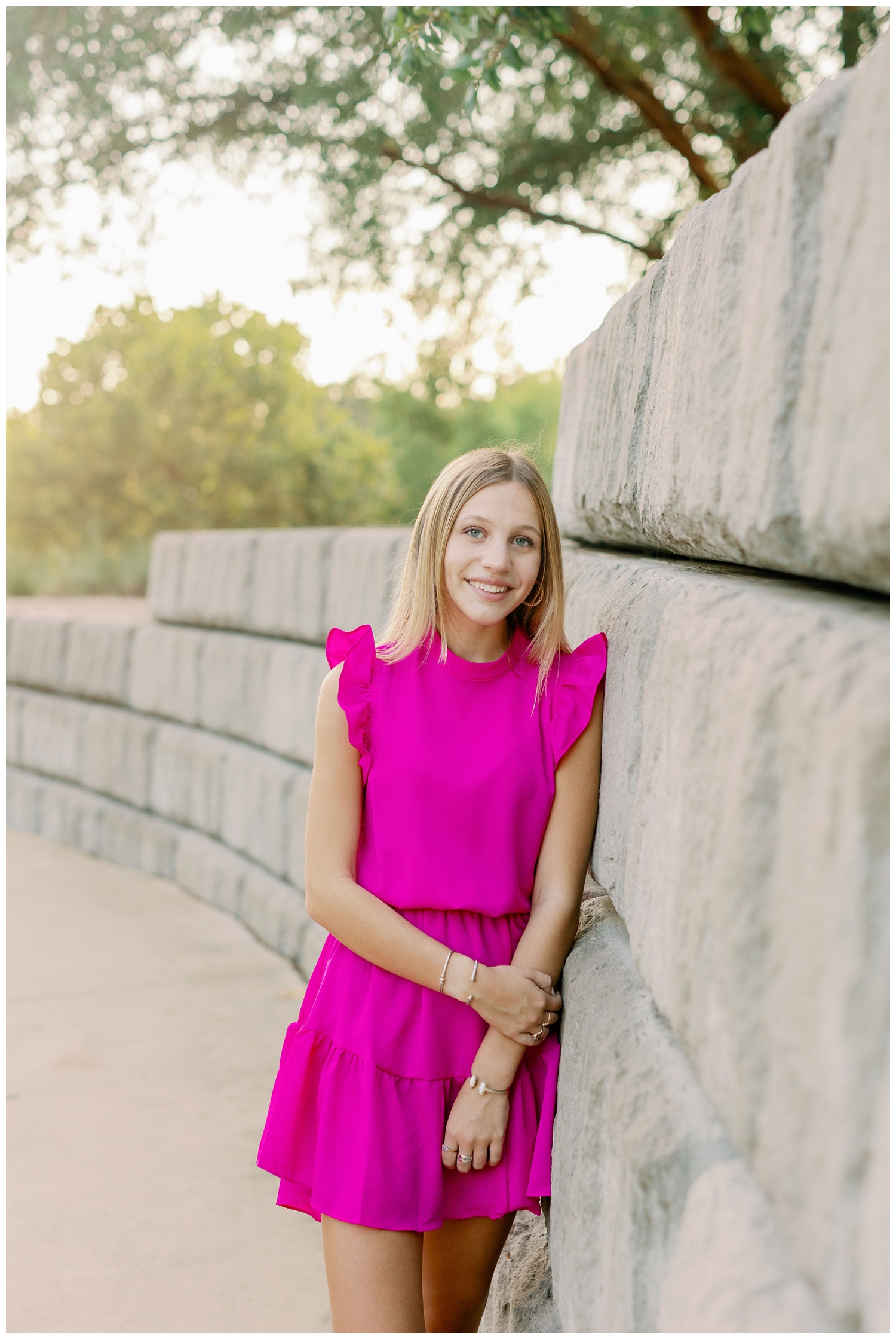 girl in hot pink dress standing against gray column wall in Buffalo Bayou