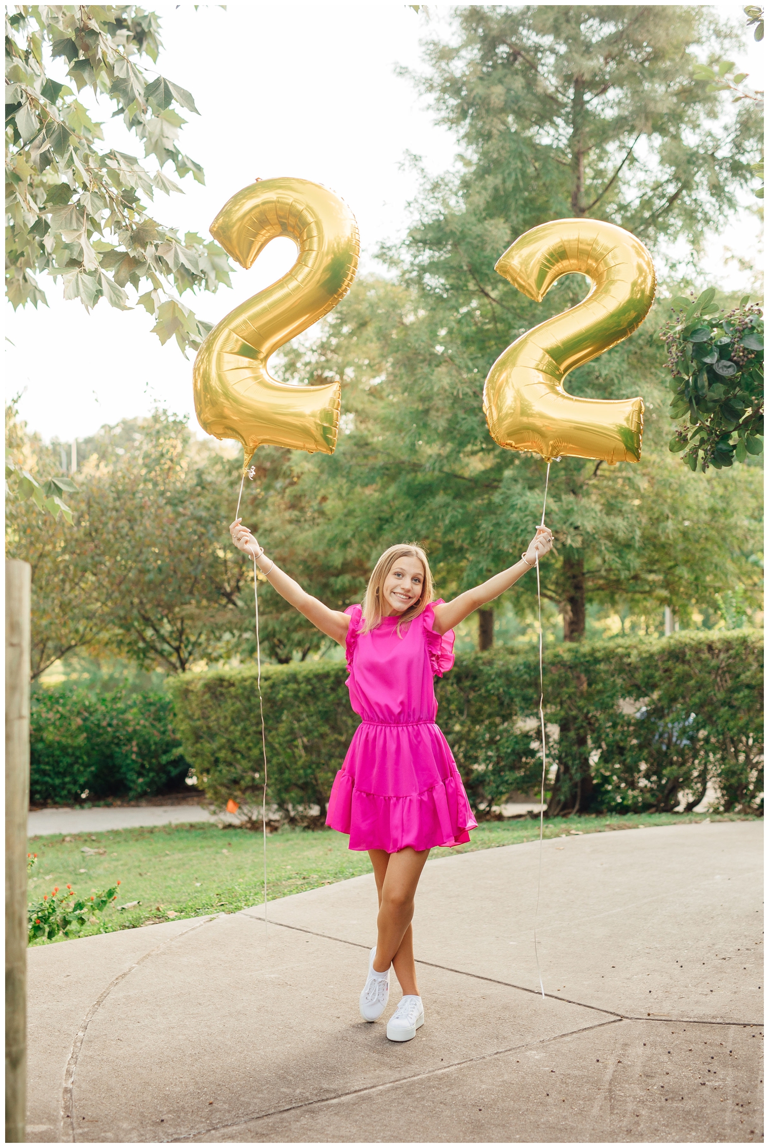 Houston senior pictures with balloons standing on sidewalk holding up 22 balloon