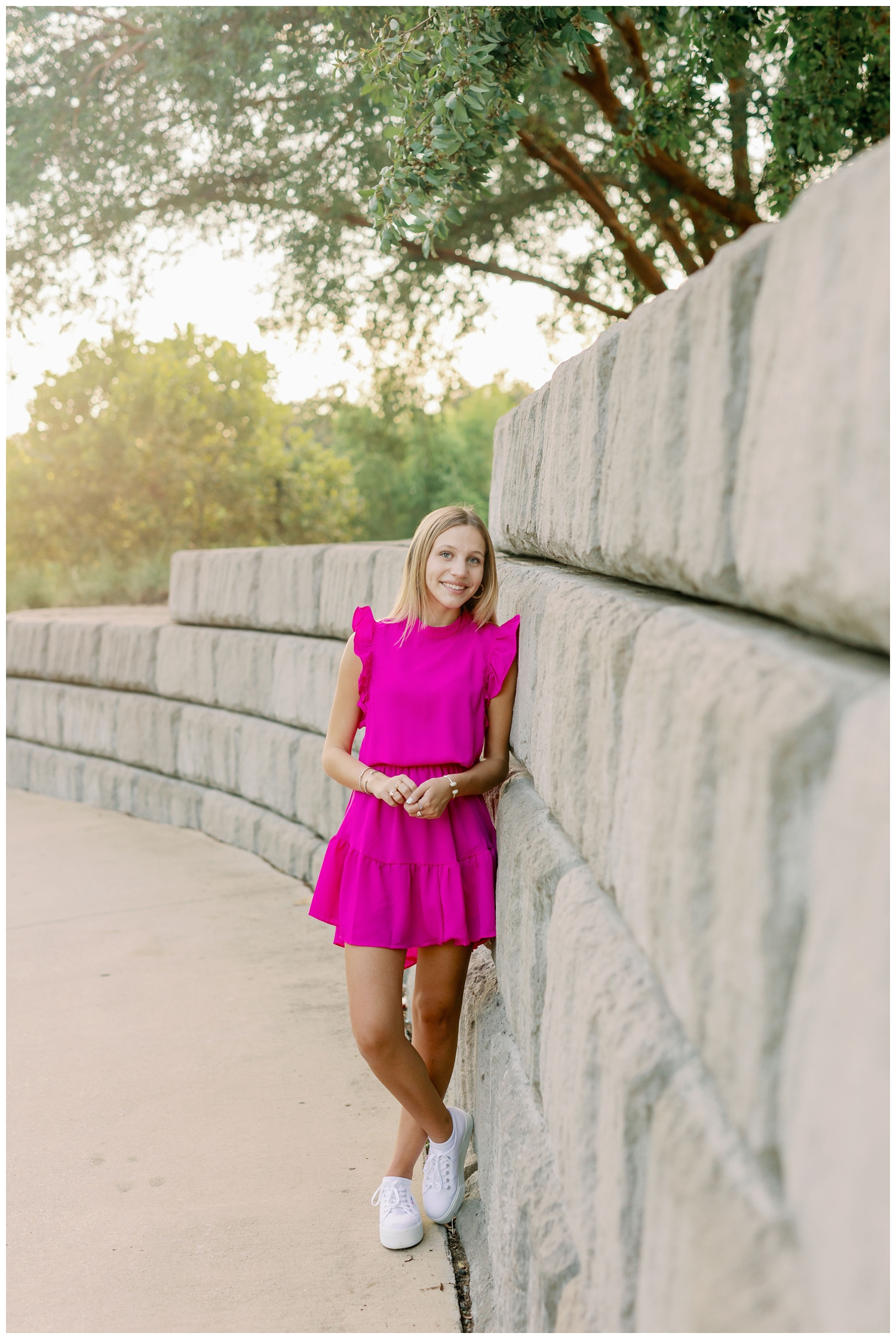 Houston senior pictures with balloons standing against gray wall at Buffalo Bayou Park