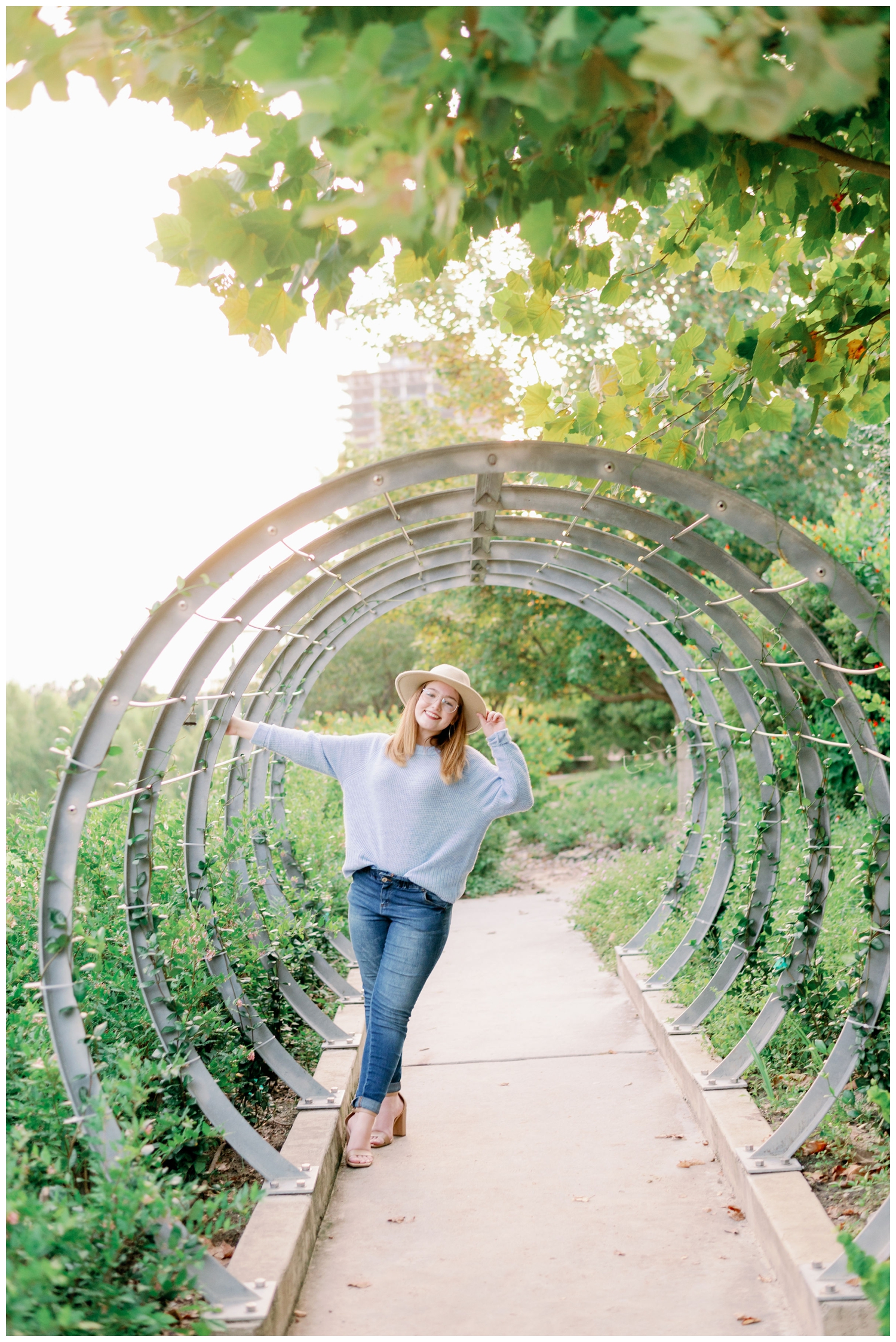 girl in jeans and blue shirt standing in rings with greenery at Buffalo Bayou