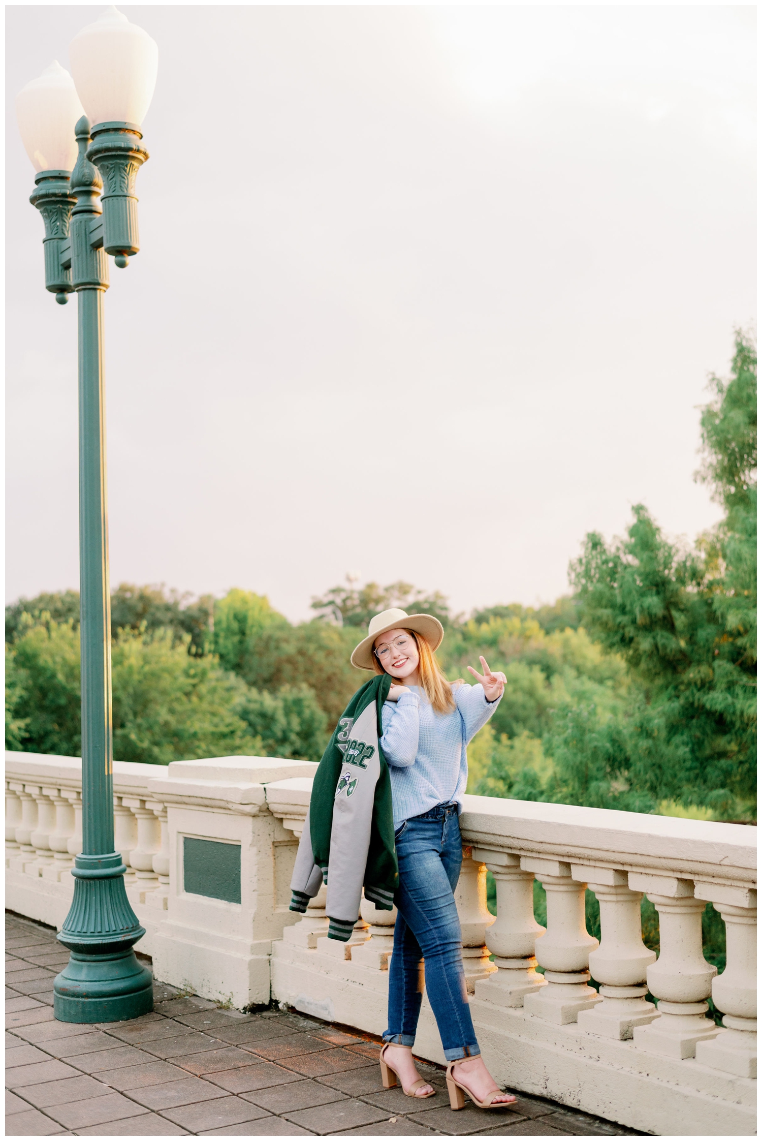 girl standing on Sabine Bridge holding letter jacket senior pictures downtown Houston