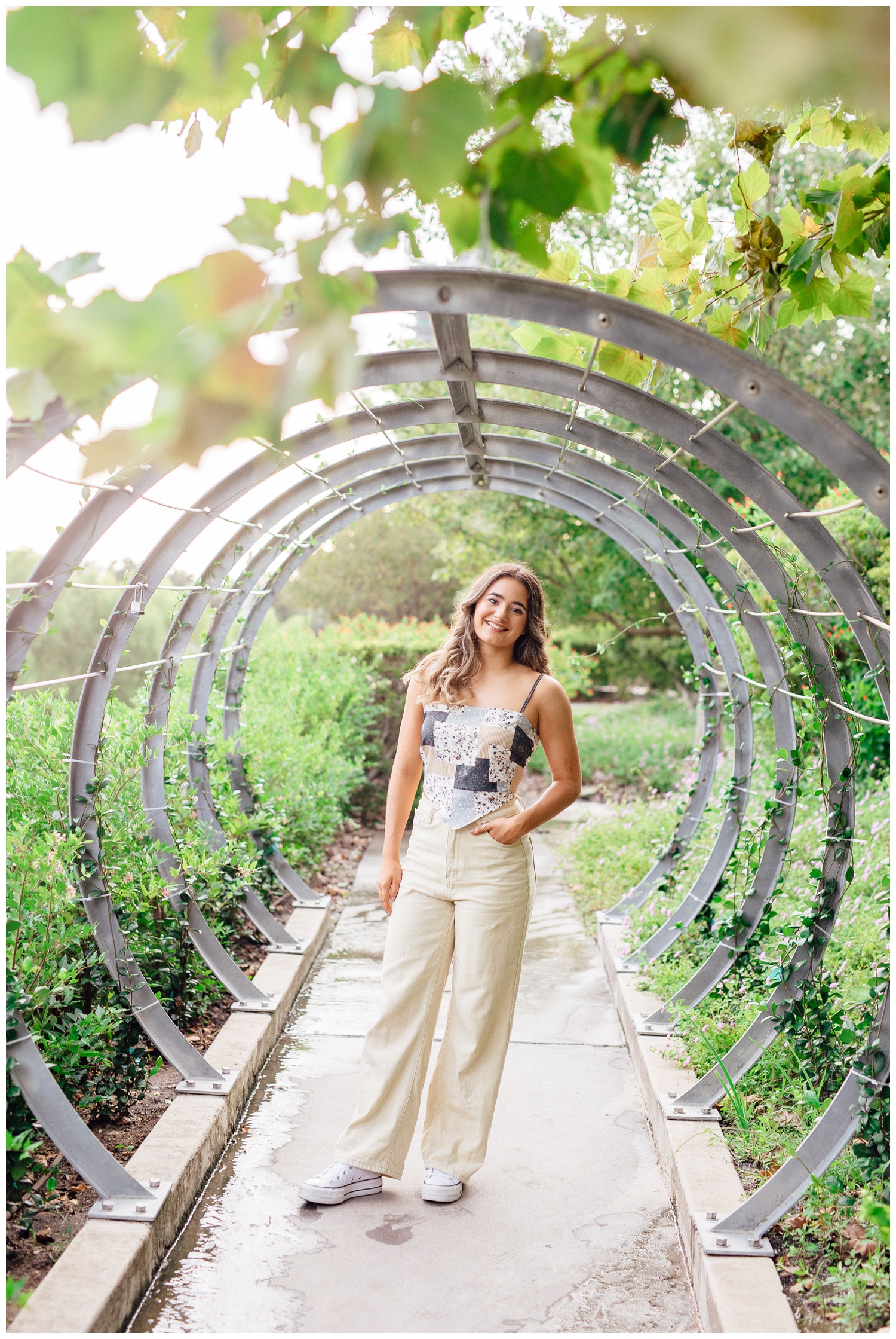 senior girl in cream jeans and patched tank standing inside rings at Buffalo Bayou Park for Houston senior dance photographer