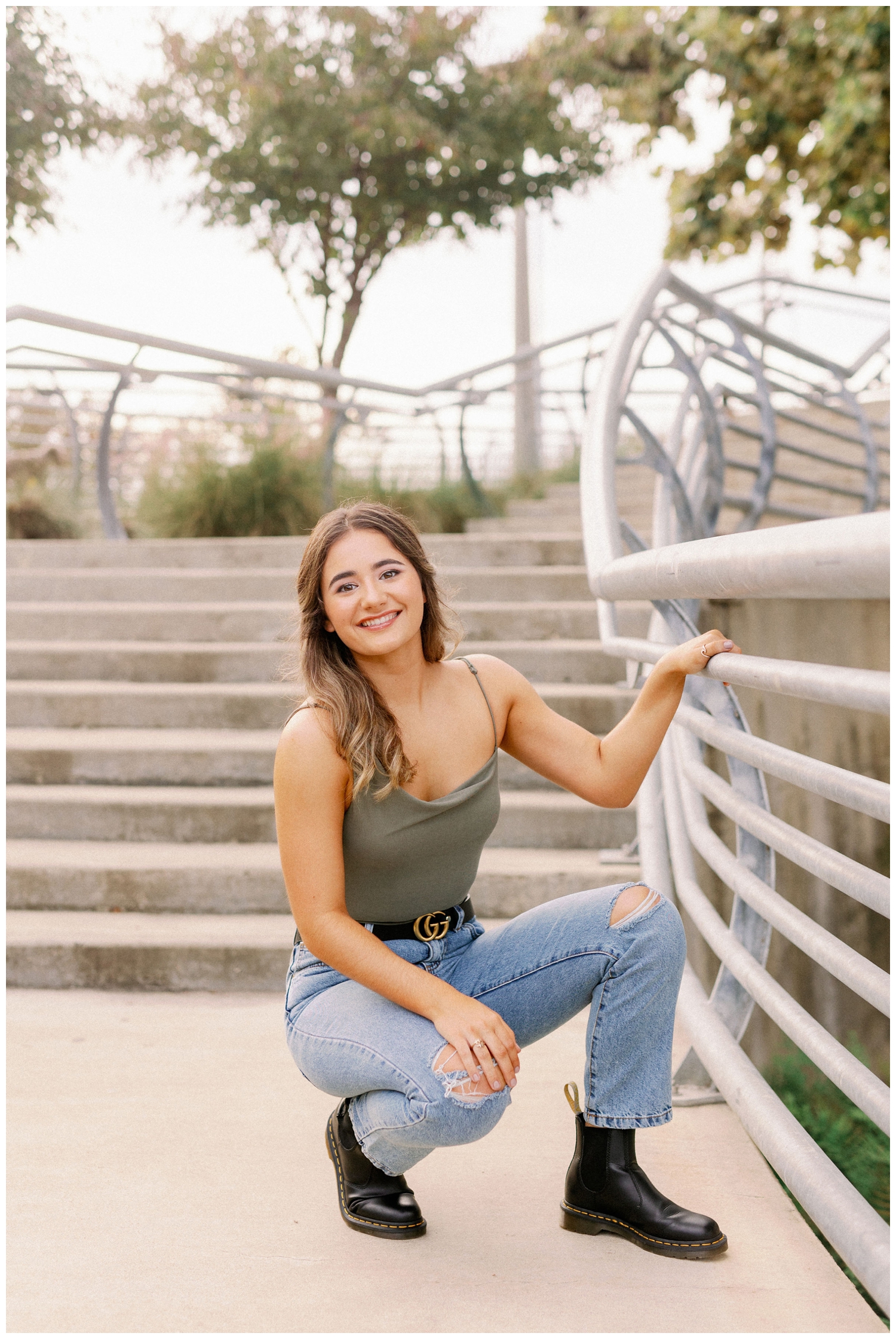 girl squatting in jeans and green tank holding on to stair rail downtown Houston