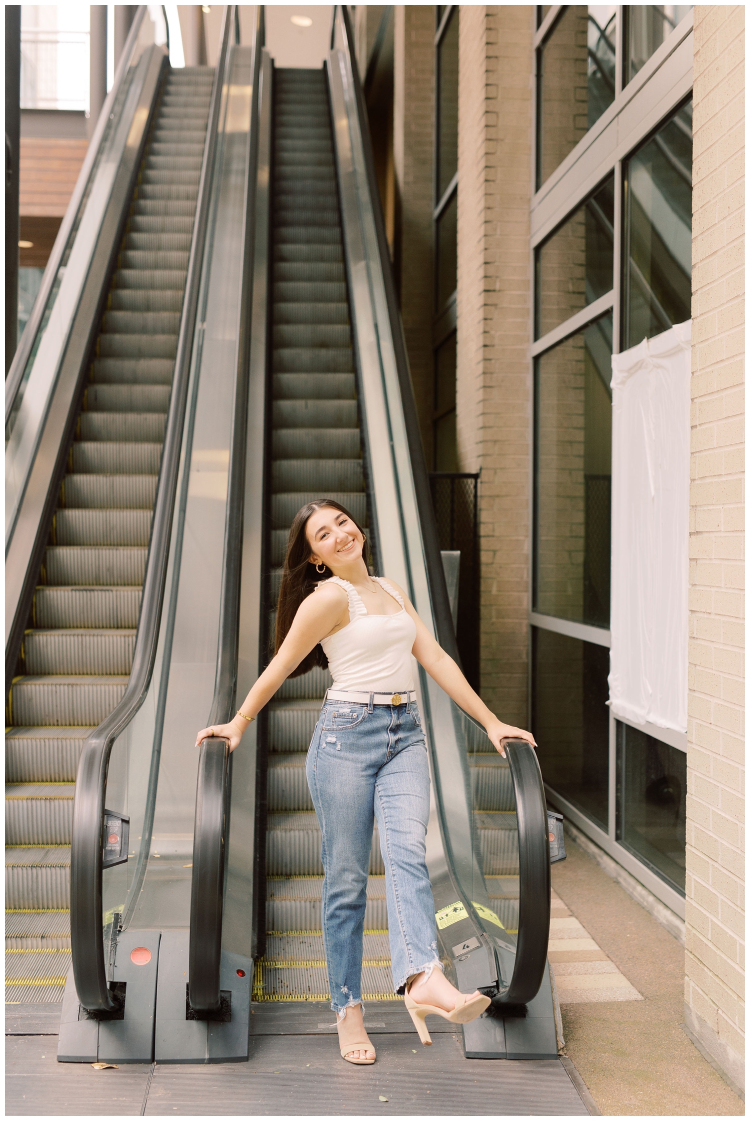 girl in denim jeans and white tank shirt on escalator downtown Houston Main Street