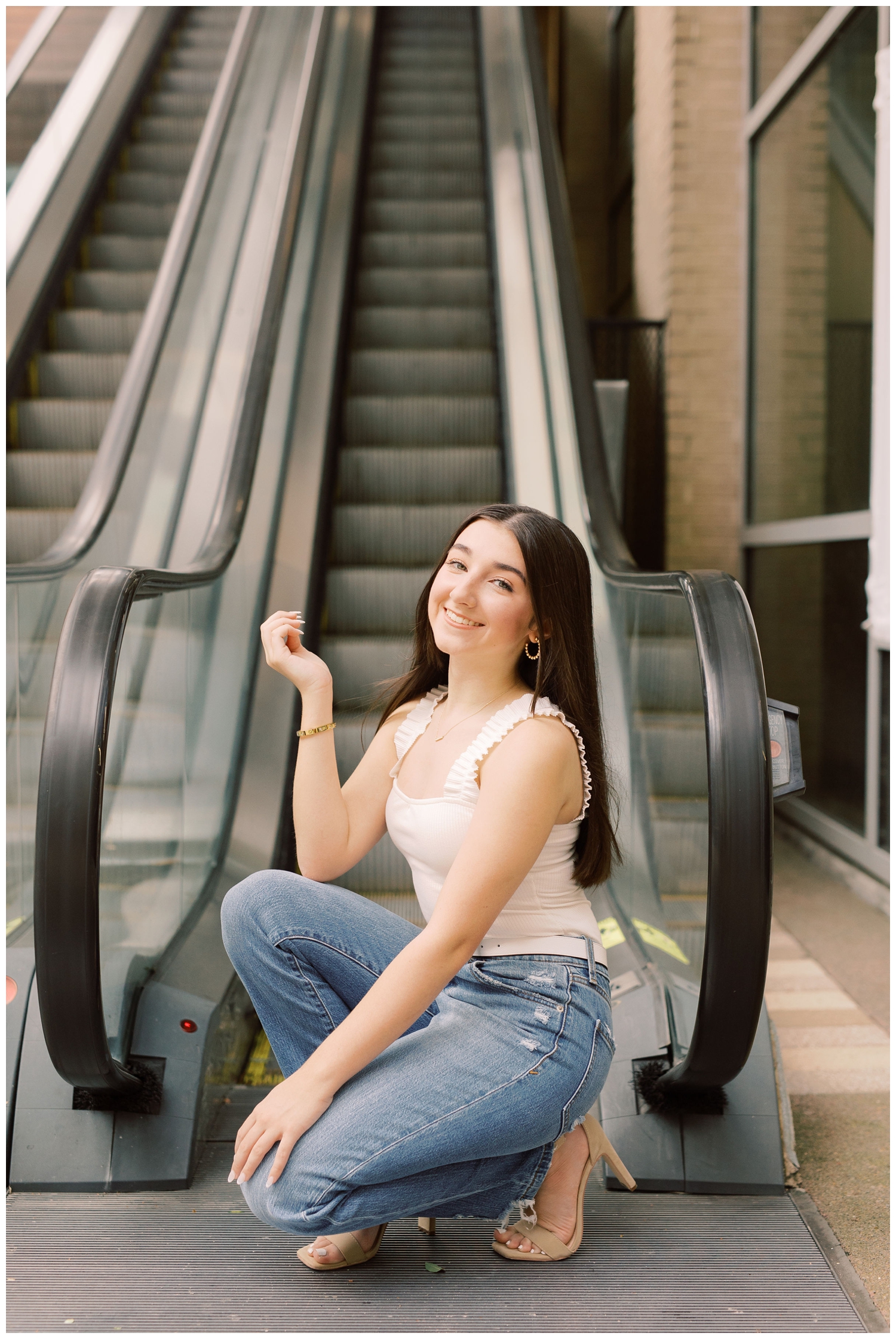 girl kneeling in front of escalator for urban Houston senior photographer