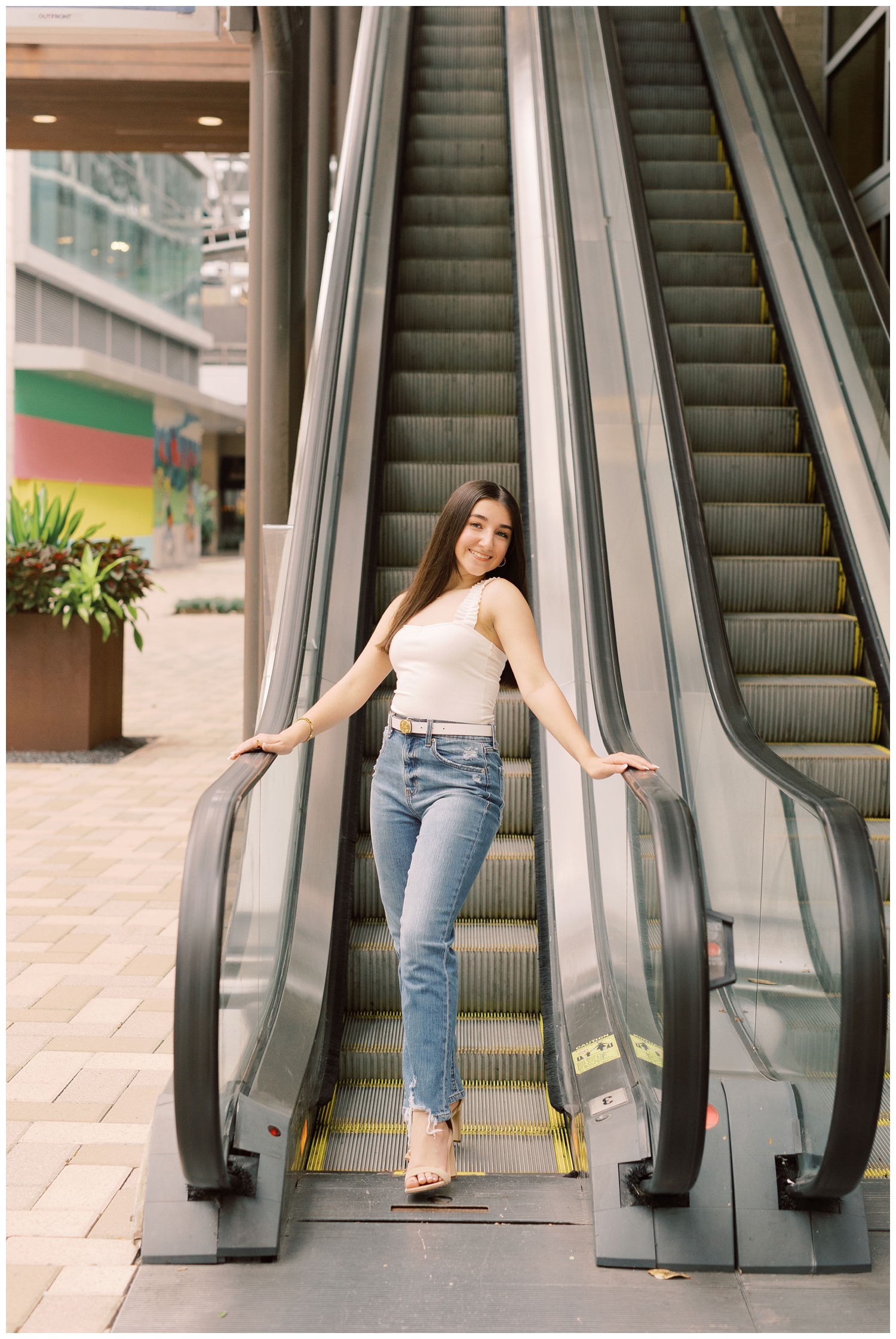 girl in denim jeans and white tank on escalator urban Houston
