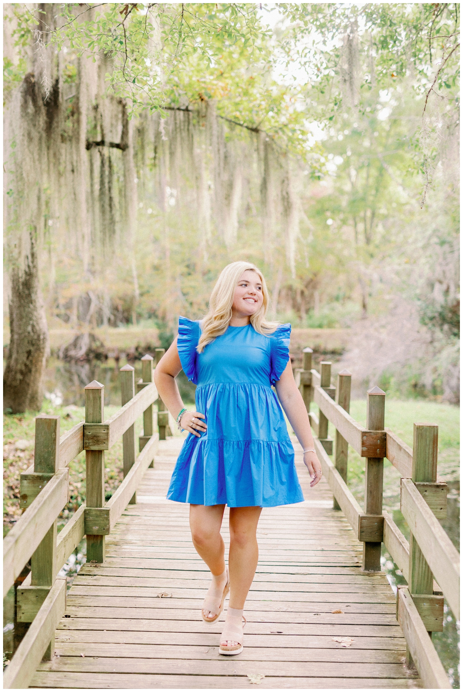 girl walking in bright blue dress on bridge under mossy trees at Cy-Hope in Cypress, Texas