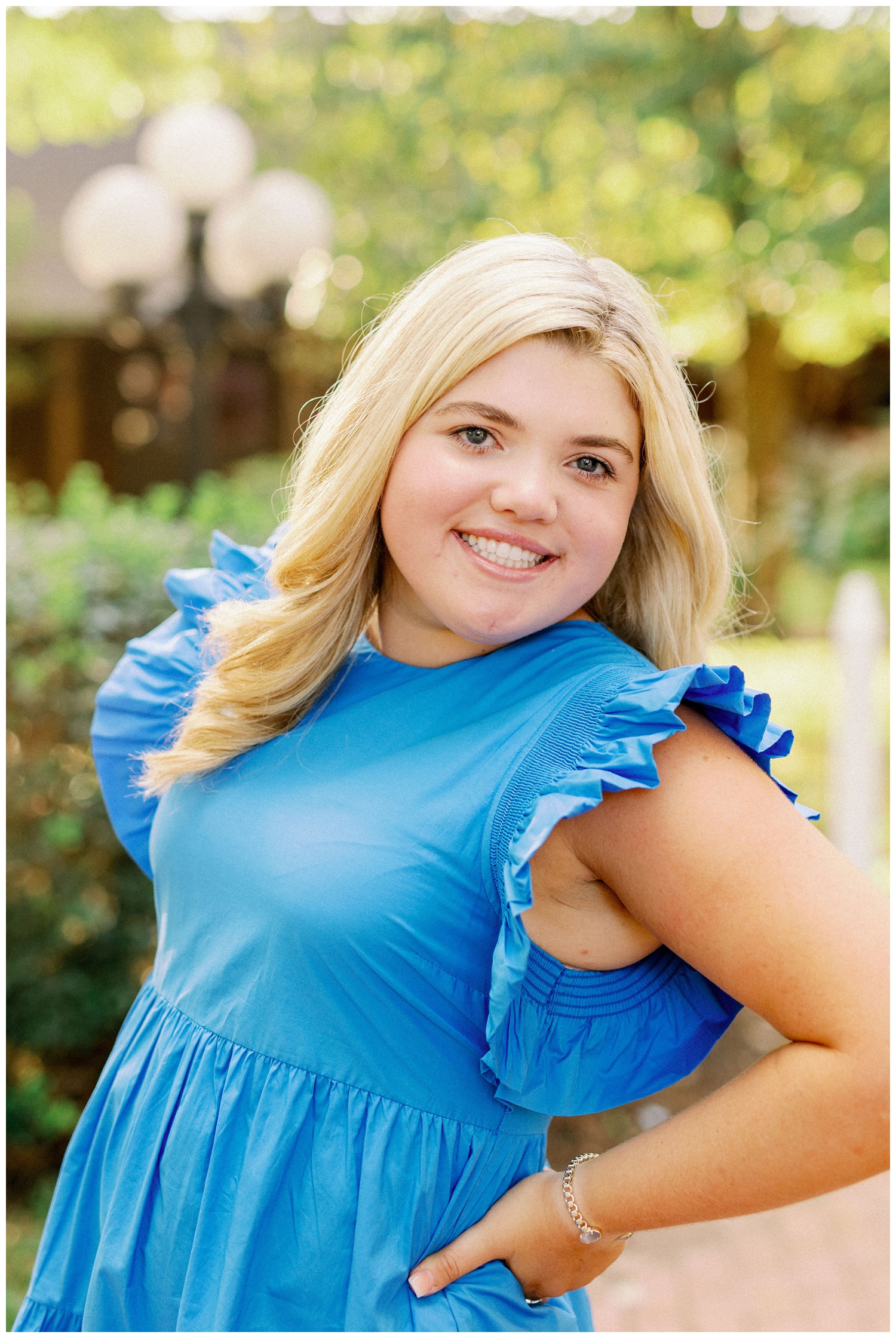 girl smiling in bright blue dress for colorful Houston senior photography in Cypress, Texas