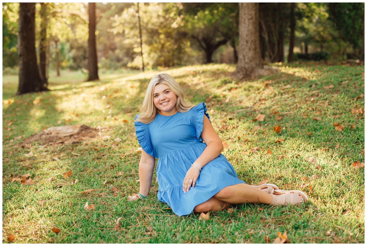 Houston senior in bright blue dress sitting on grass smiling