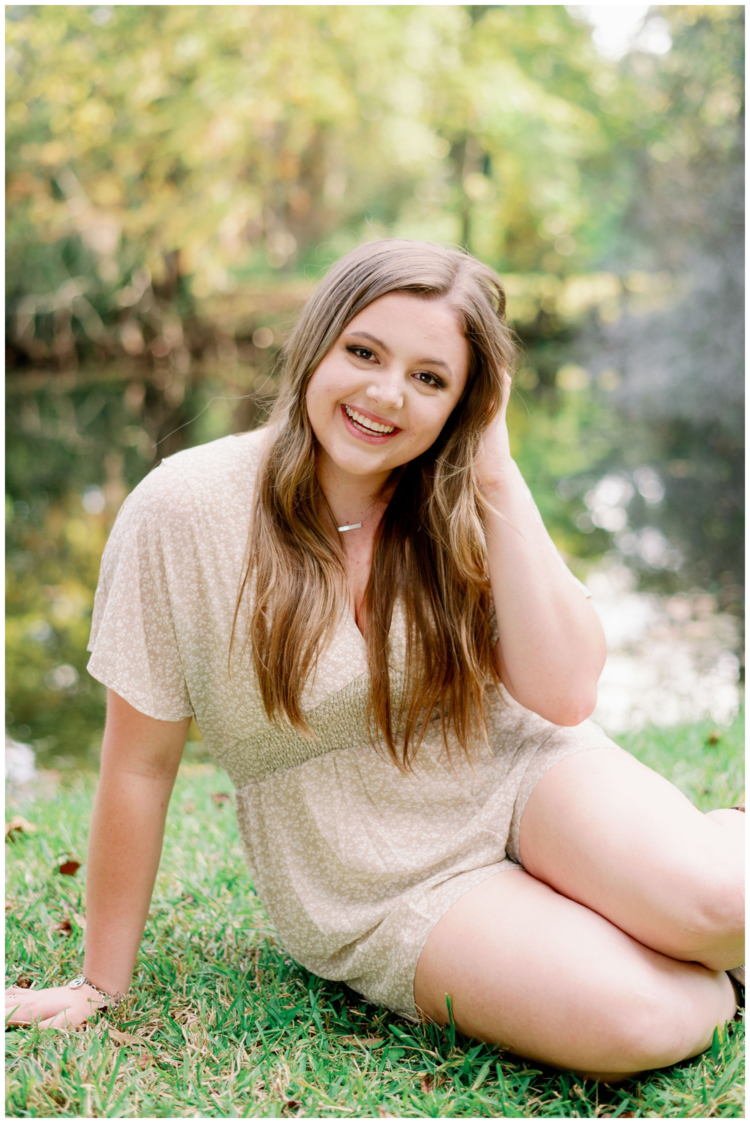 girl sitting on grass with hand in hair Cypress senior photography