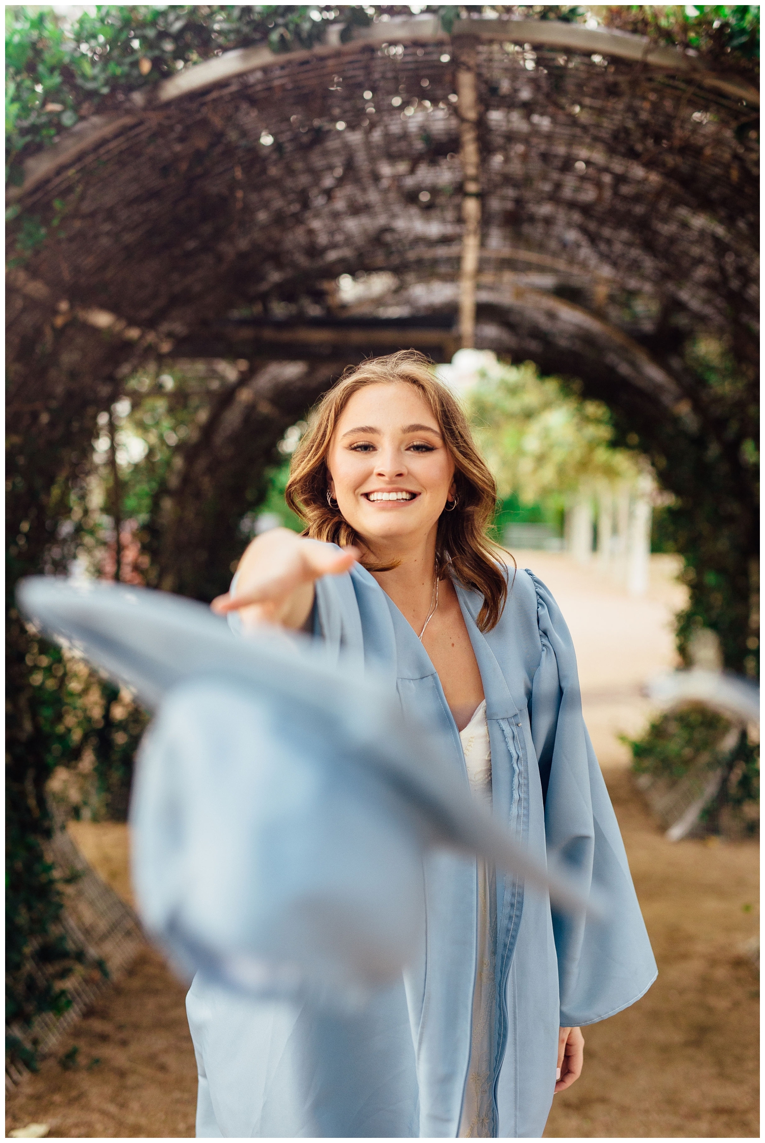 girl smiling and throwing graduation cap for senior pictures in Houston