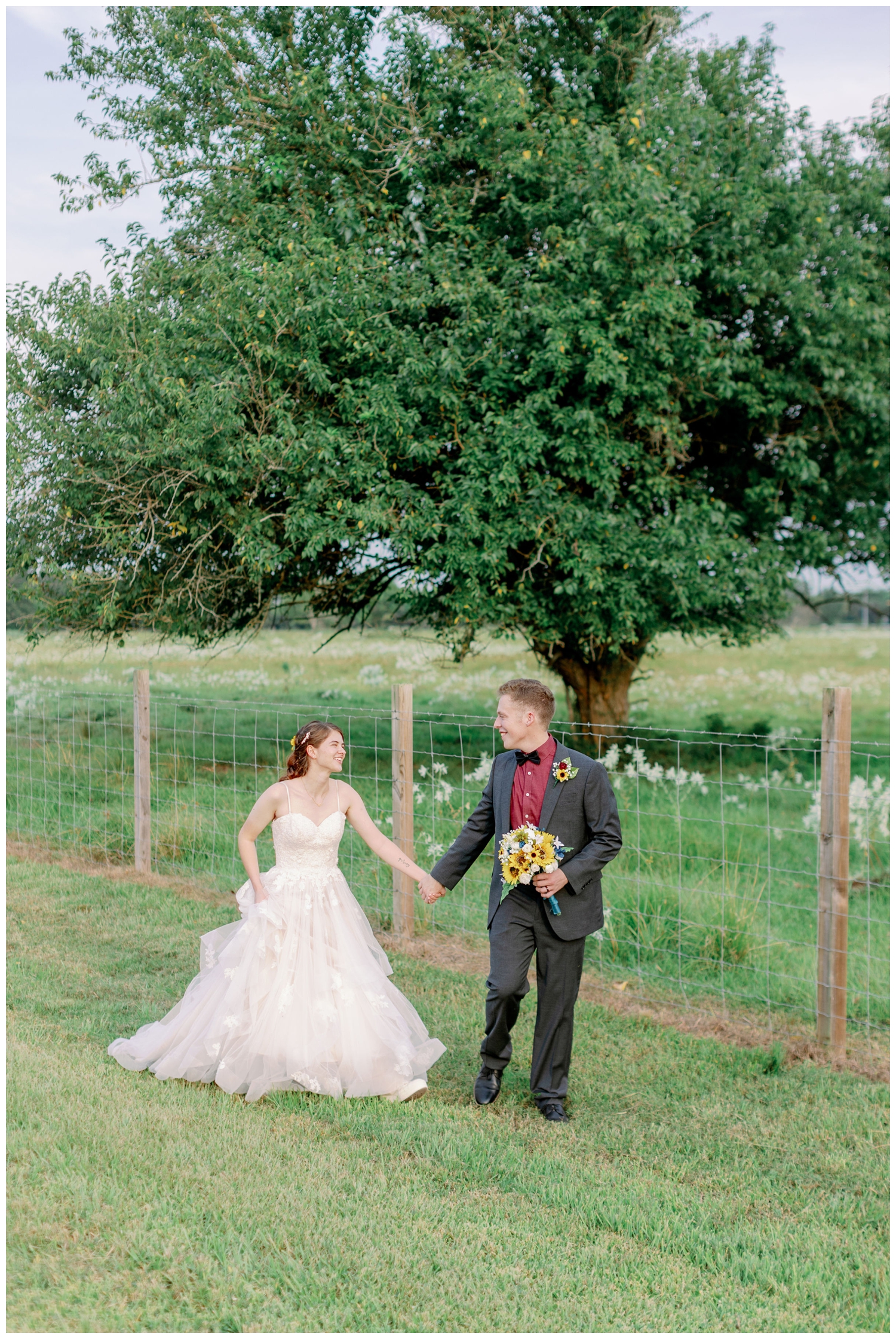 bride and groom walking by a field