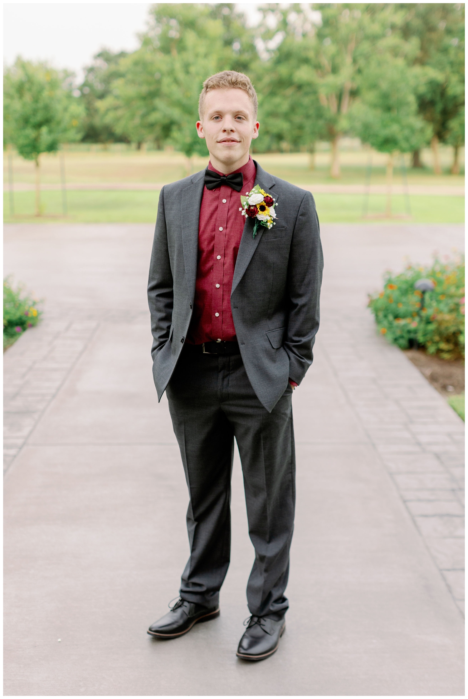groom in suit with burgundy shirt standing on path The Oaks at the Oak Plantation wedding
