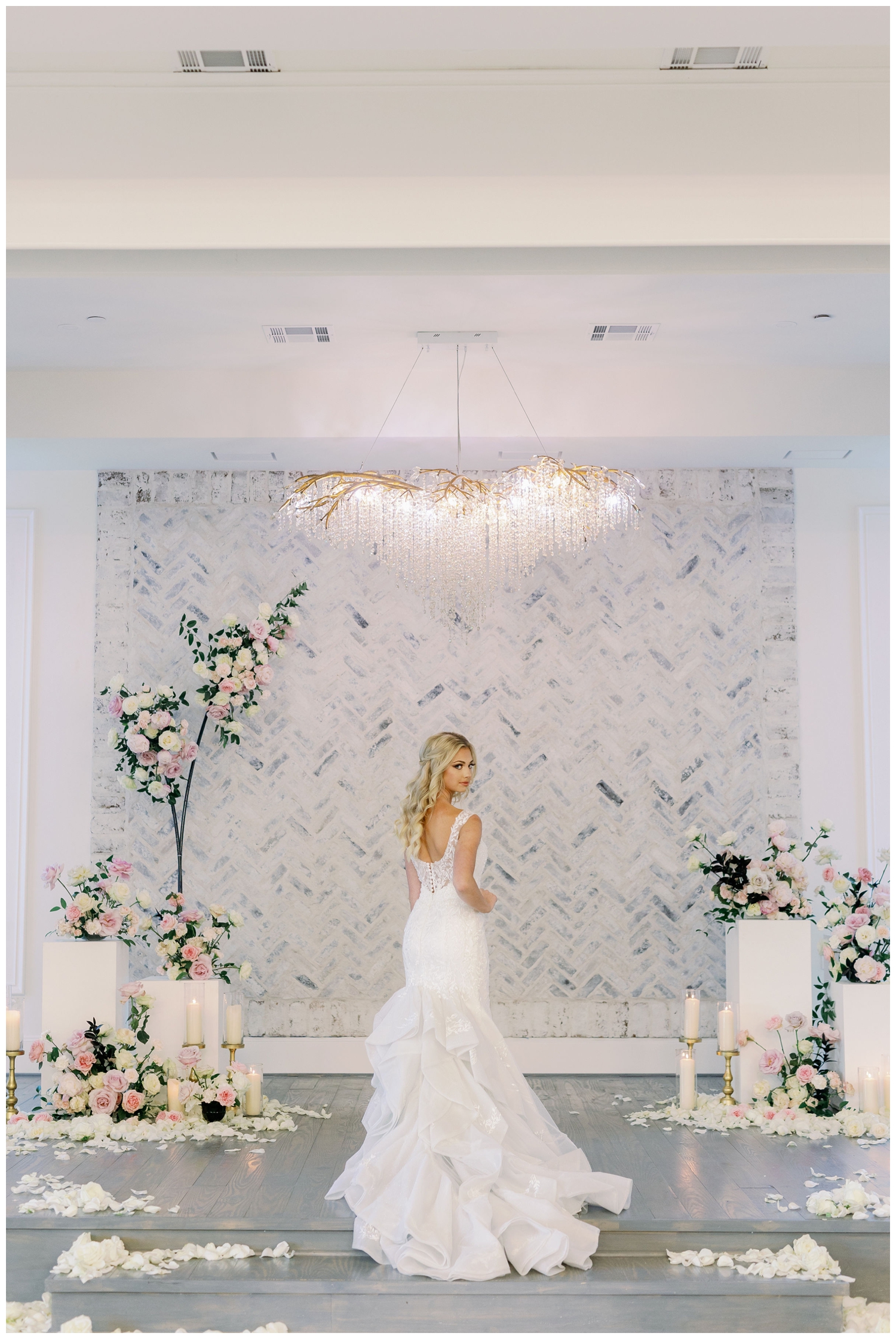 bride standing in front of gray wall inside The Peach Orchard Venue with floral arch