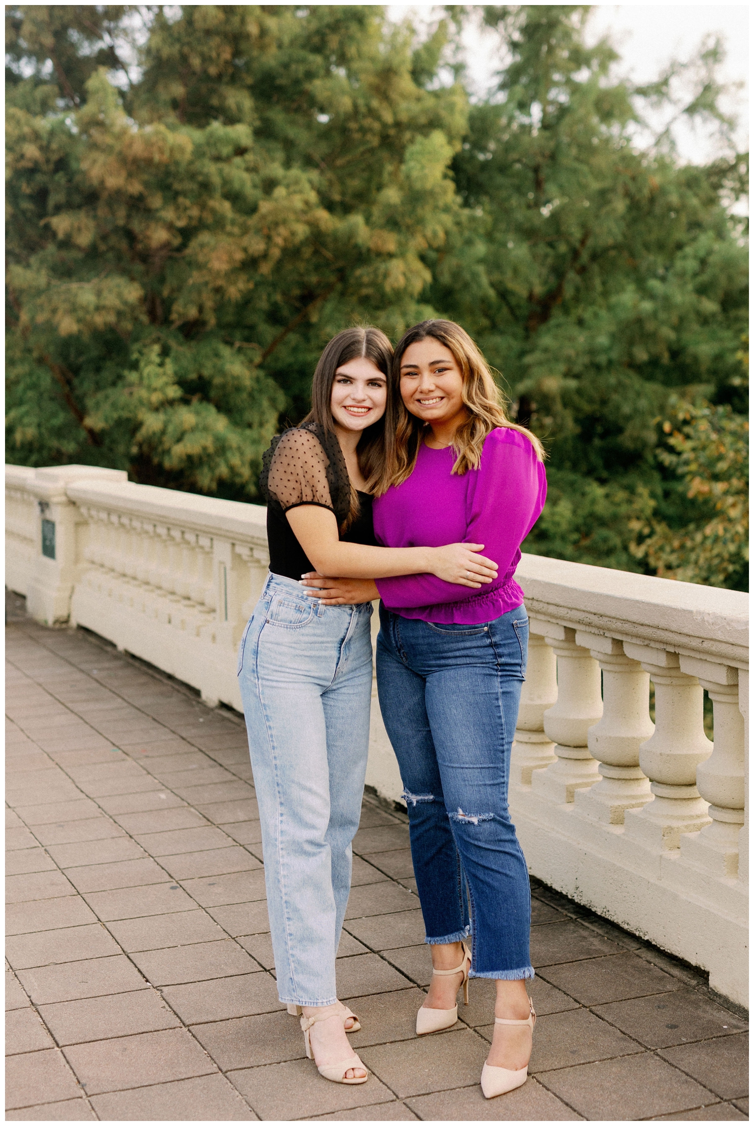 Dawson High School seniors in jeans and blouse standing in Buffalo Bayou hugging for best friends senior session portrait
