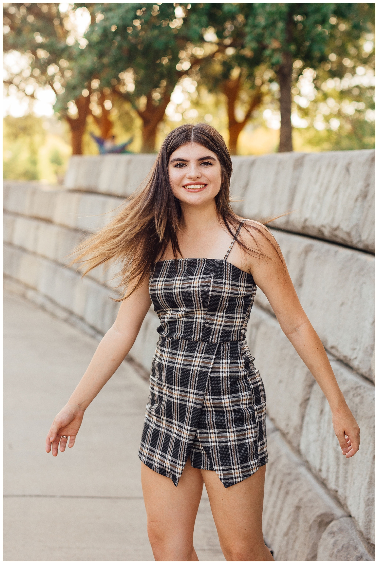 high school senior portrait with girl twirling in black plaid dress