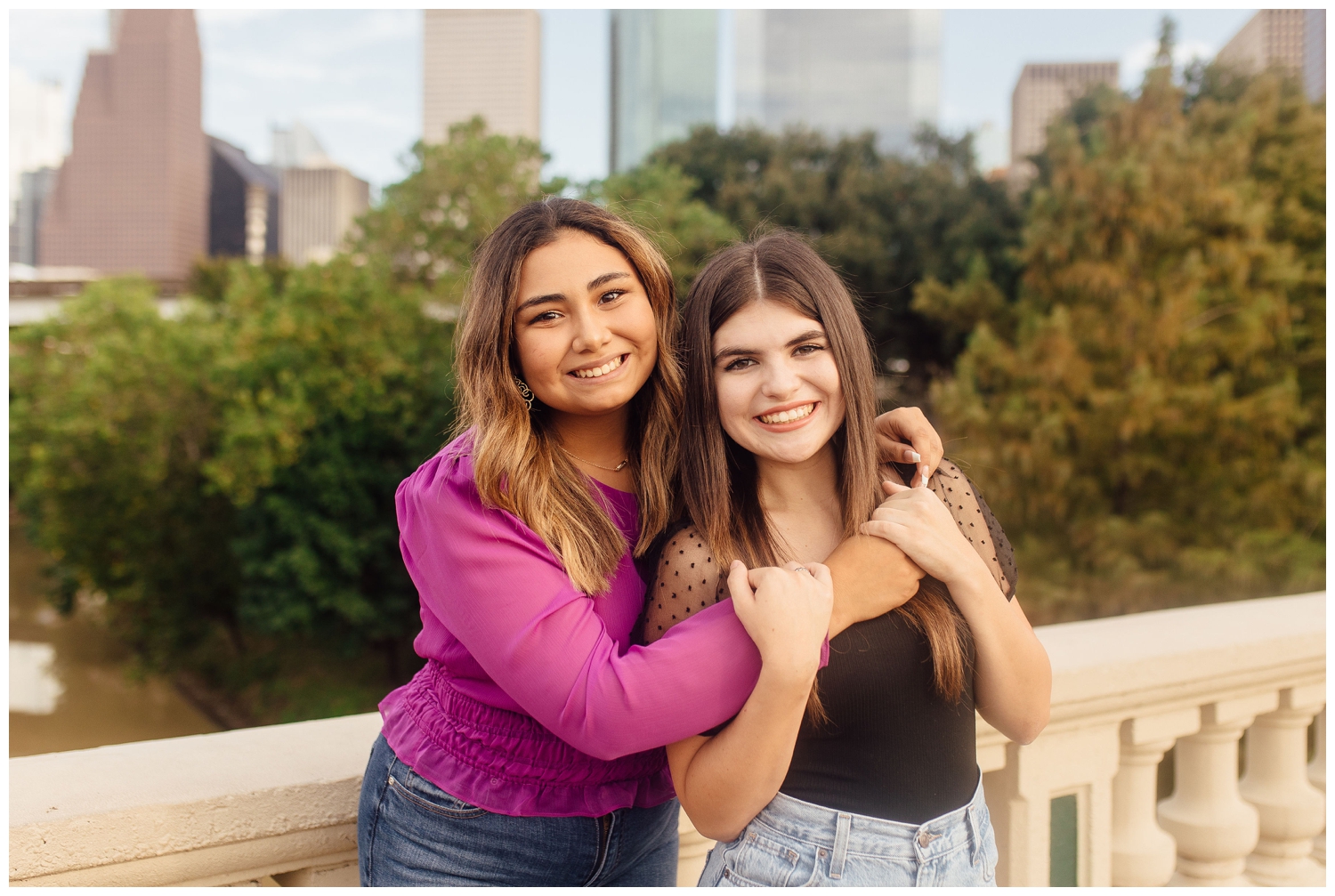 best friends senior session with two girls hugging in front of Houston skyline