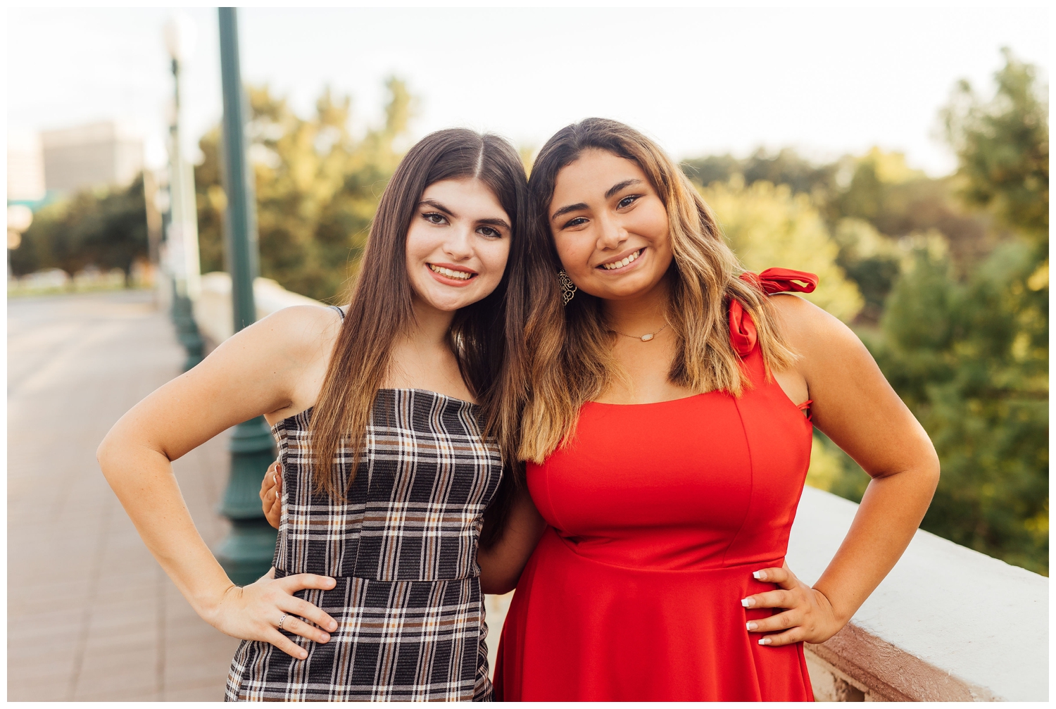 two girls in black dress and red dress with hands on hip for best friends senior session Houston Texas