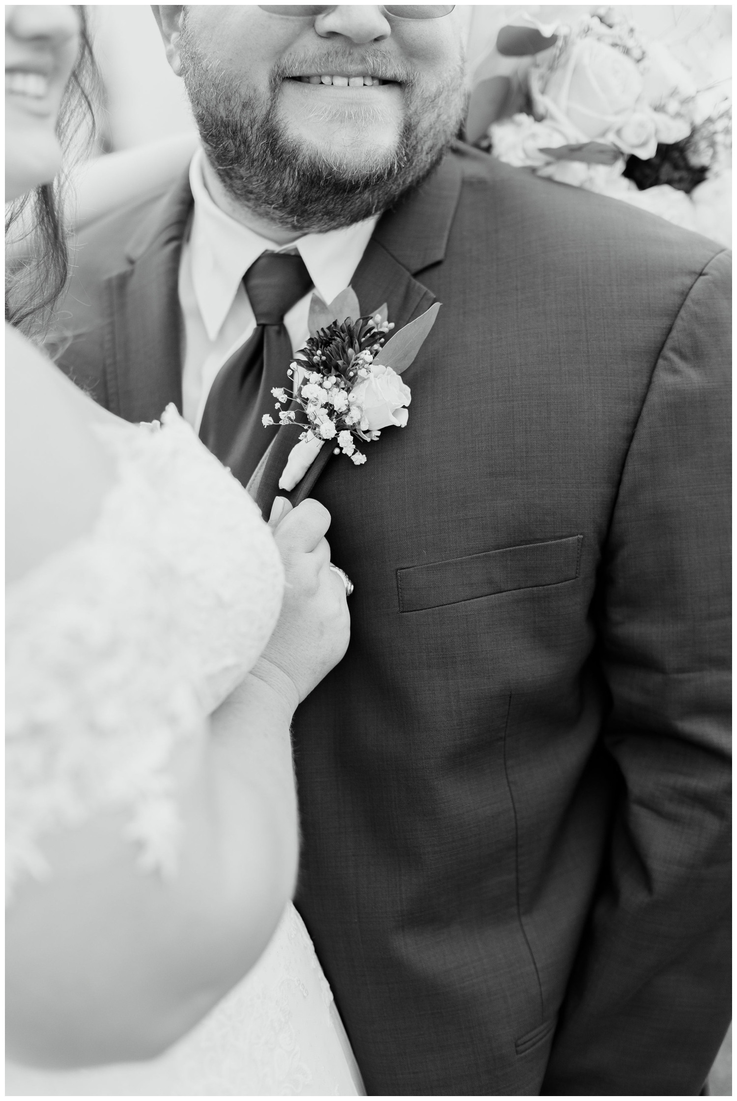 black and white detailed image of bride holding groom's jacket