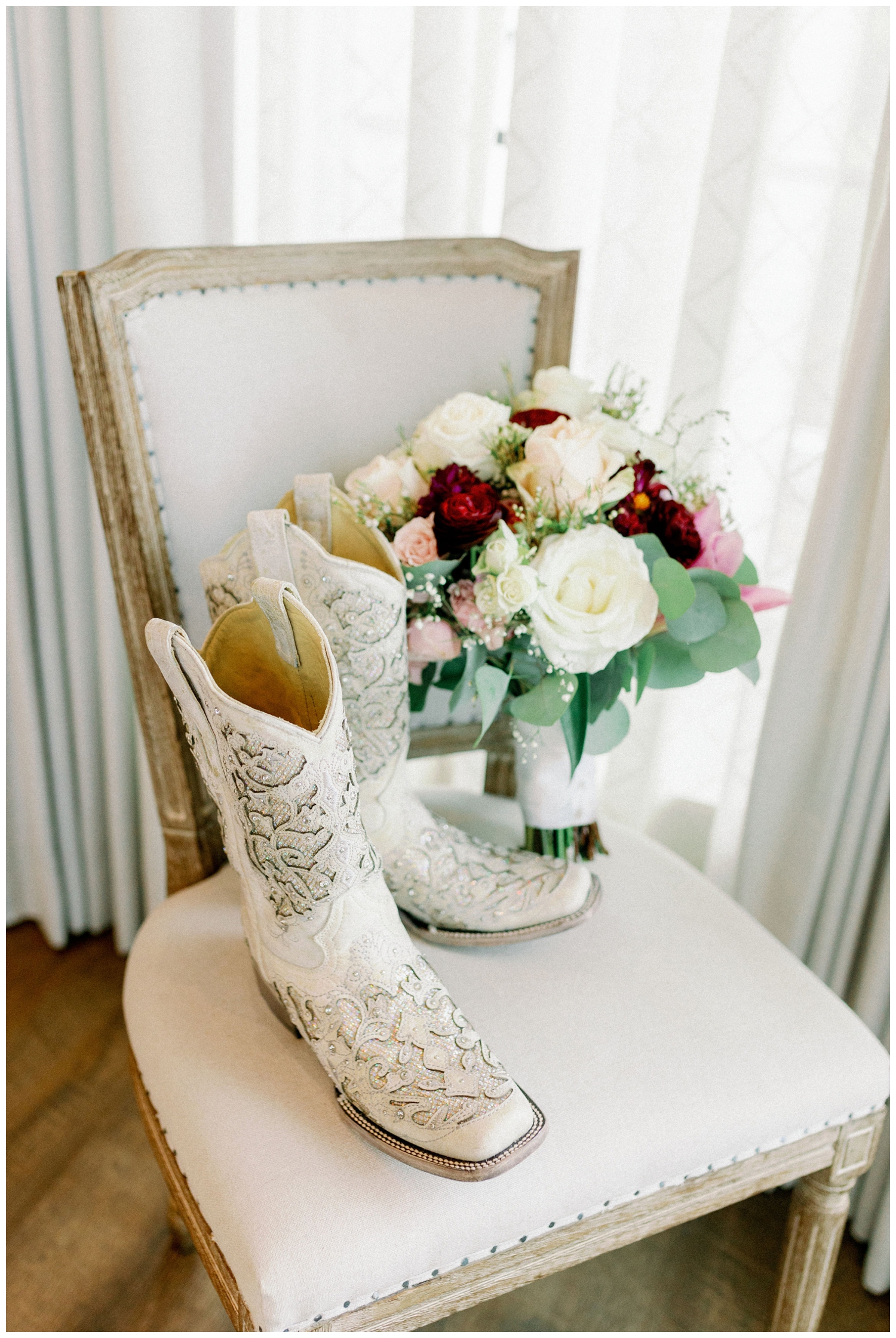 white boots and maroon and white bouquet sitting on a chair inside Deep in the Heart Farms bridal suite