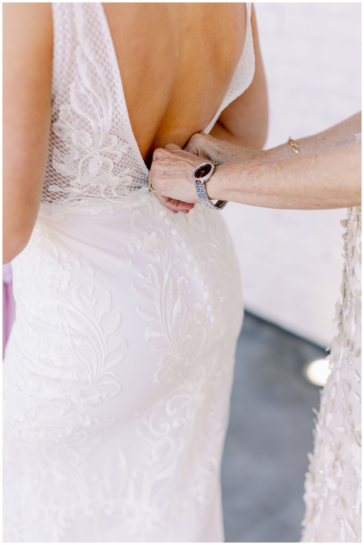 mother of bride's hands fastening wedding gown