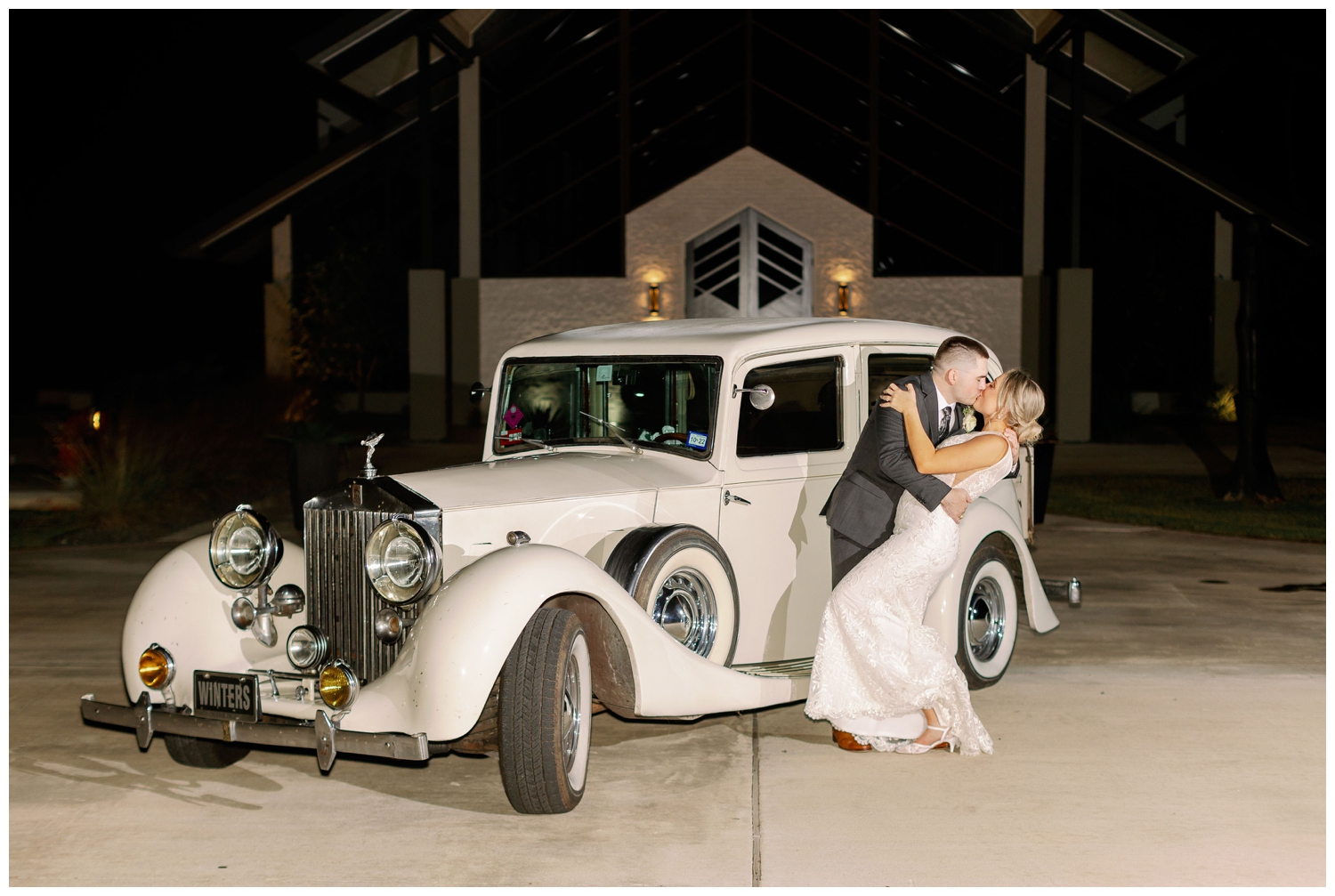 bride and groom kissing in front of white classic car